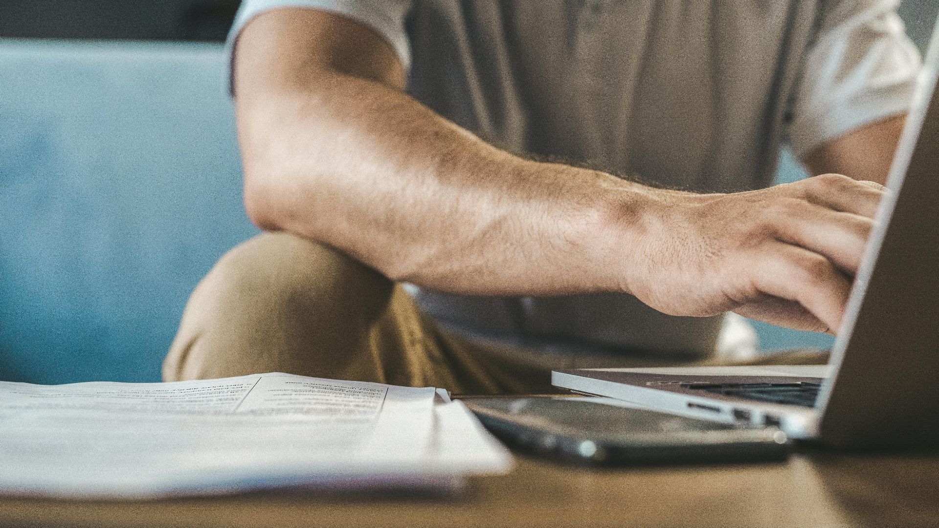 A man typing on a laptop at home, using wireless technology.