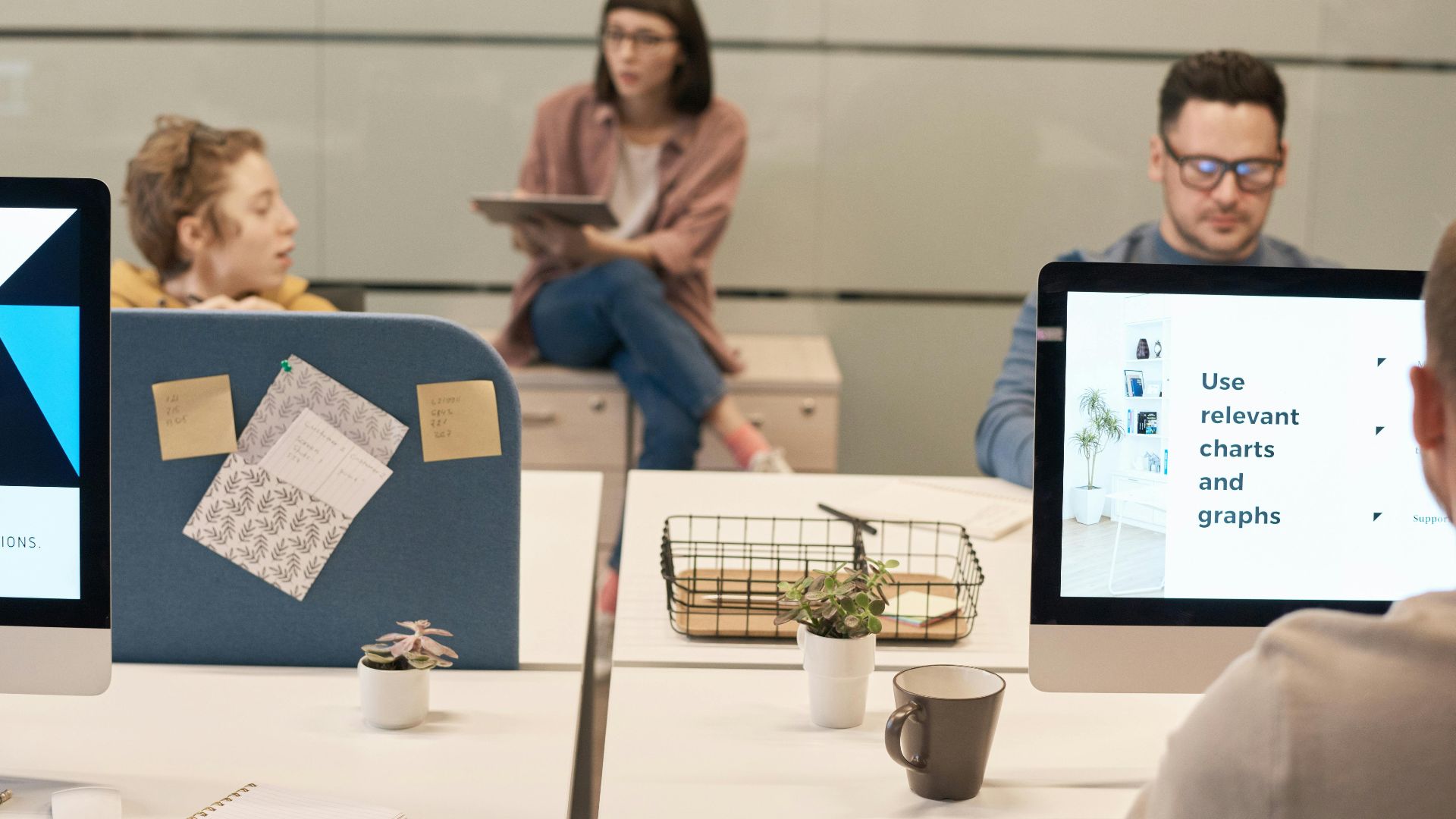 Casual office environment with team collaborating using digital devices and computers for effective project discussions.