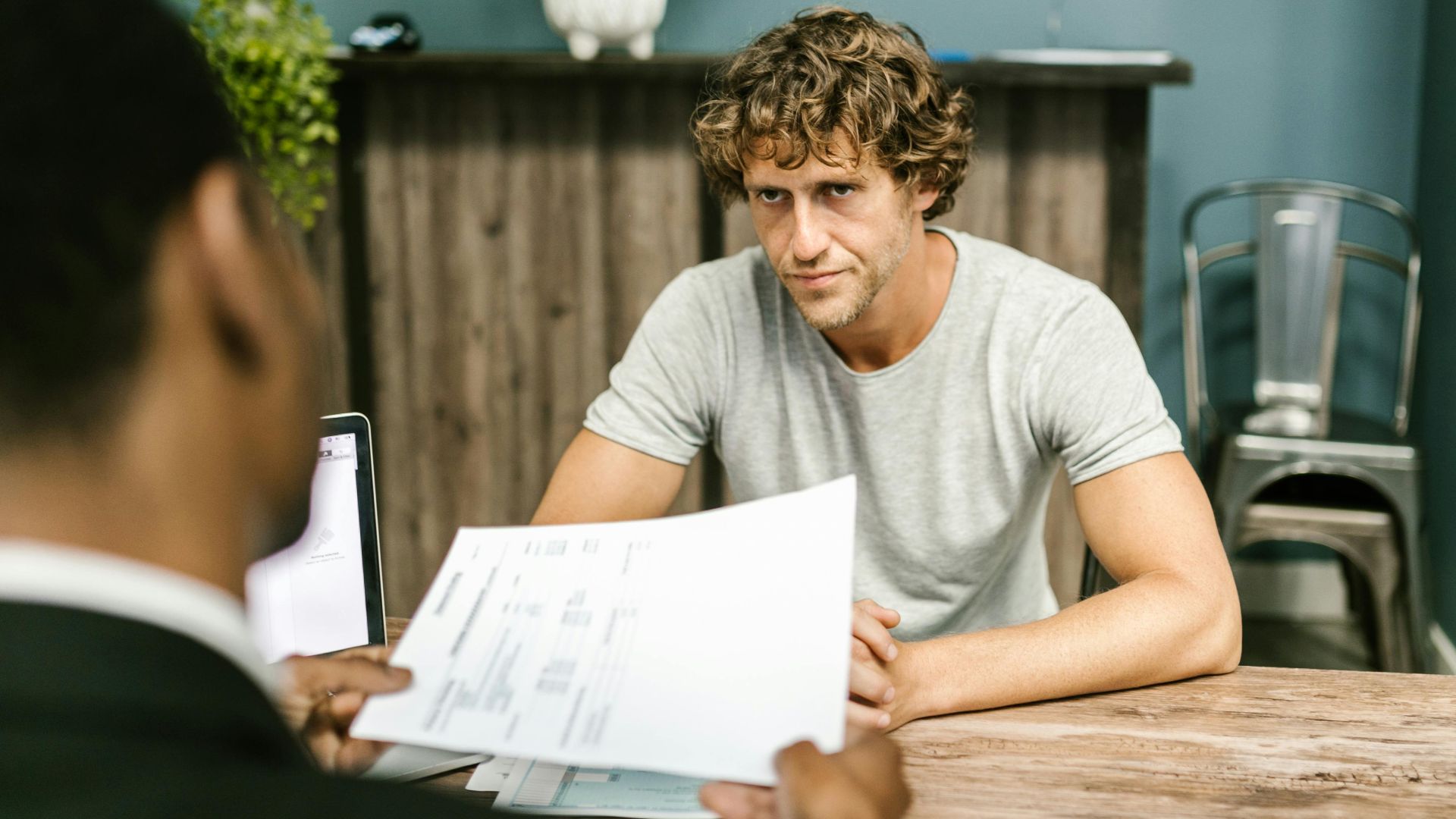 Two men in discussion over documents during a business meeting in a contemporary office setting.