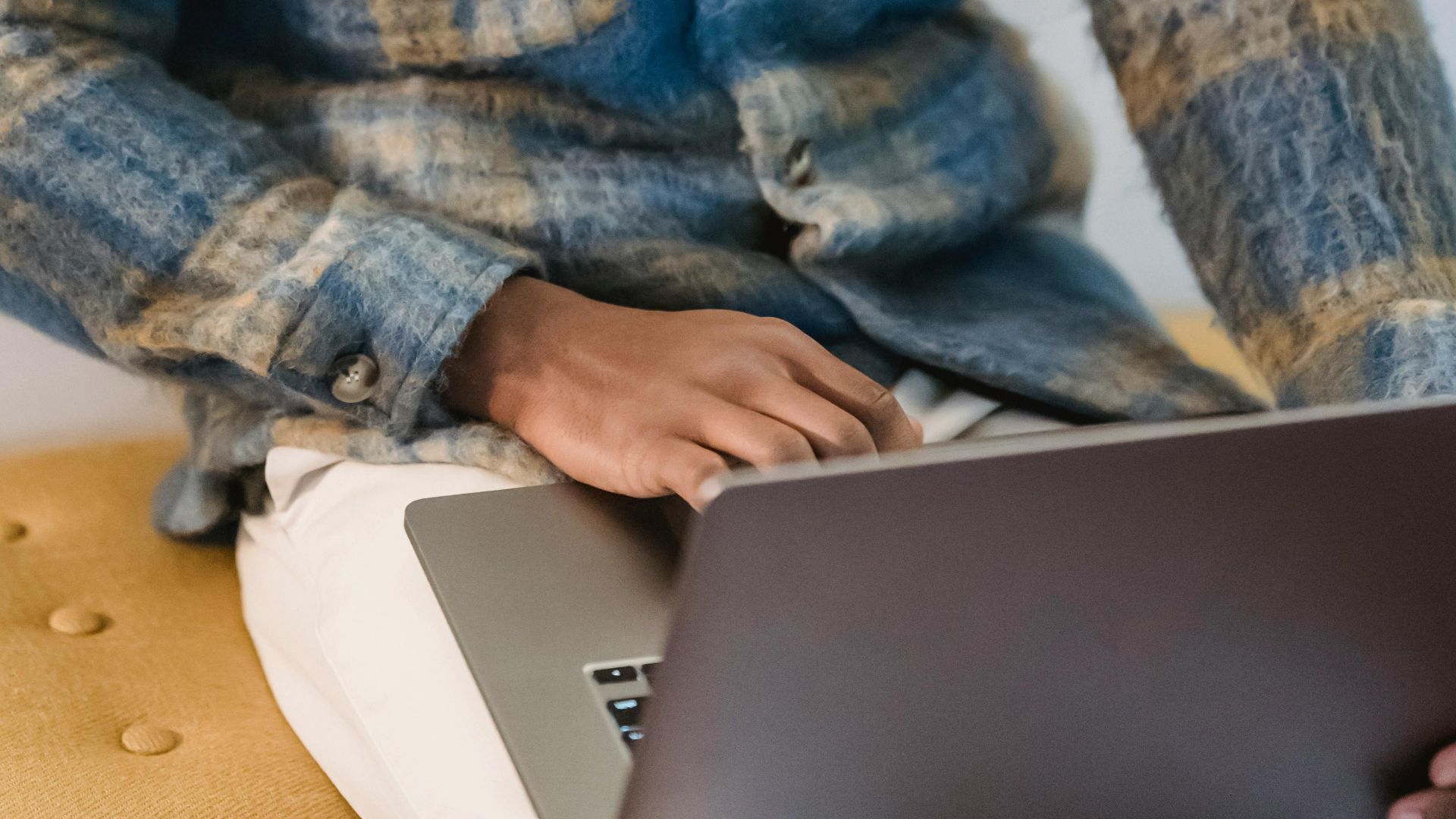 Young man in a casual setting intensely focused on his laptop, indoors.