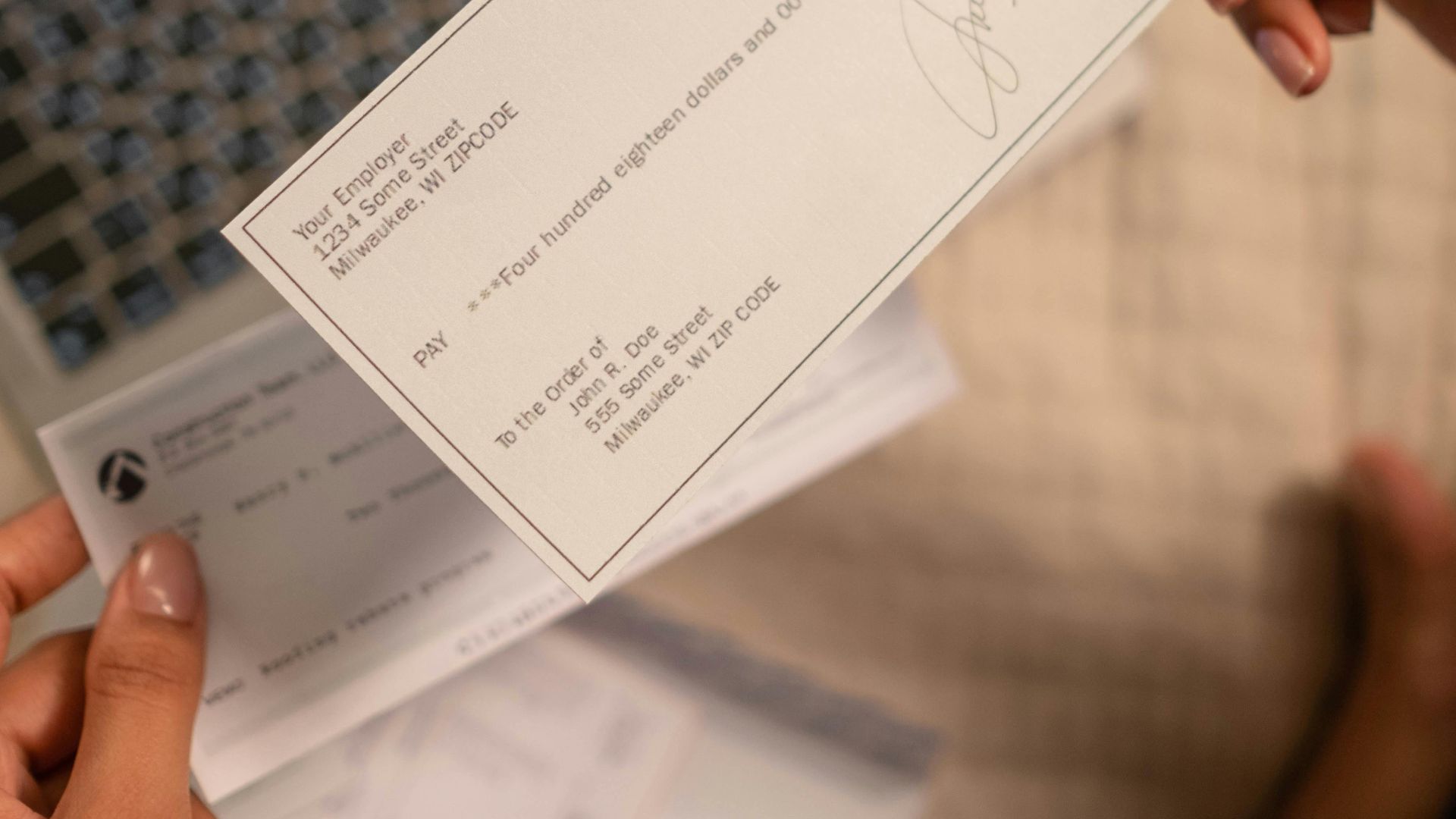 Individual holding a cheque over laptop, signifying online banking or financial transaction.