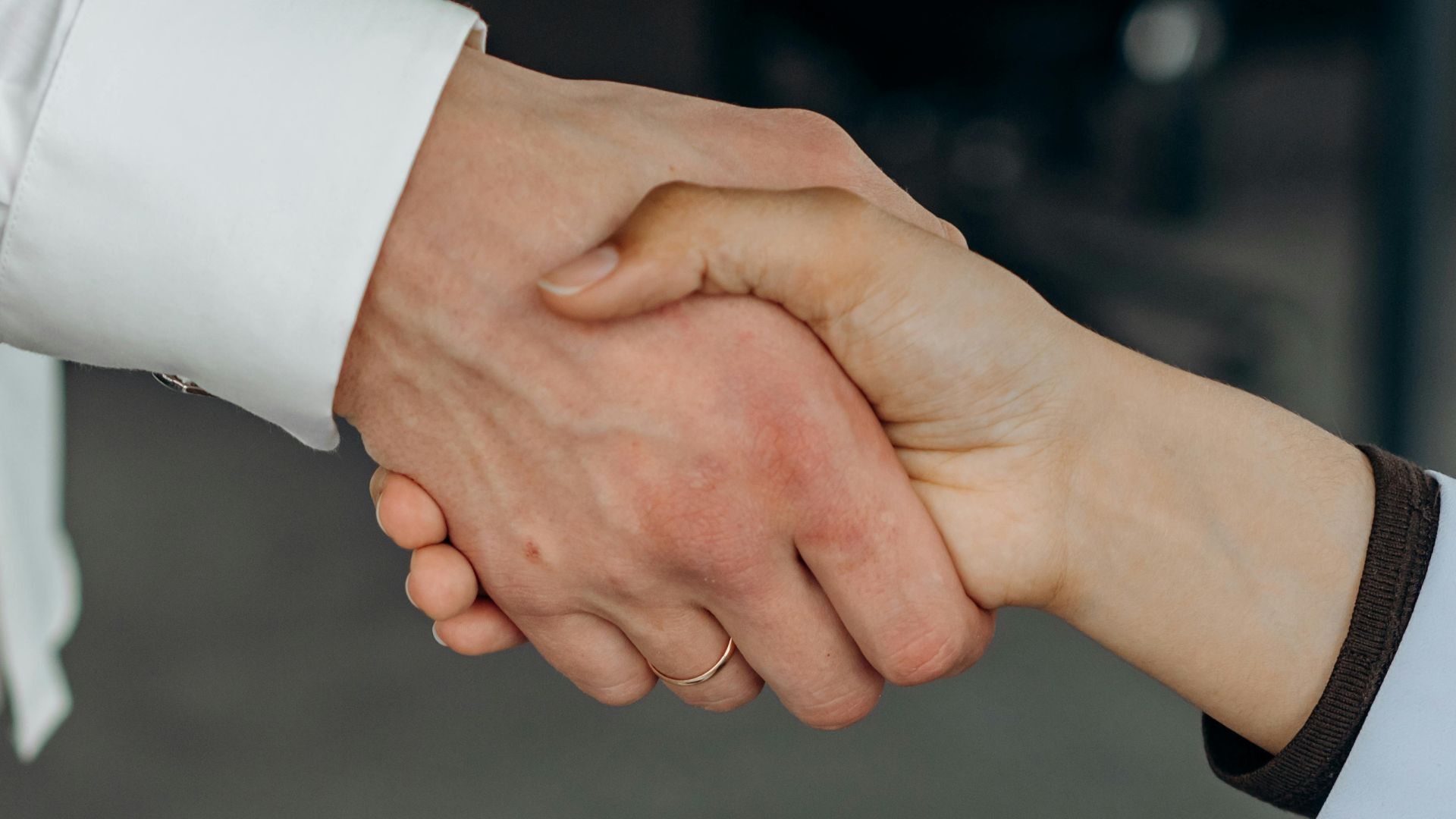 Close-up shot of two people's hands shaking, symbolizing partnership or agreement in an office setting.