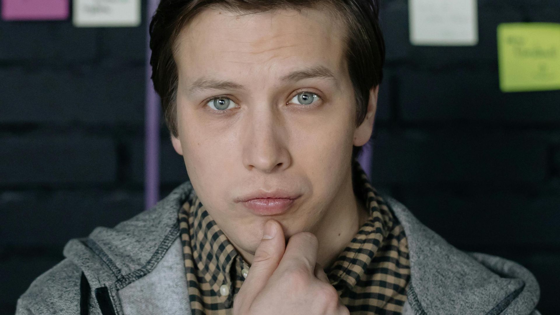 Thoughtful man pondering ideas in creative workspace with sticky notes behind.