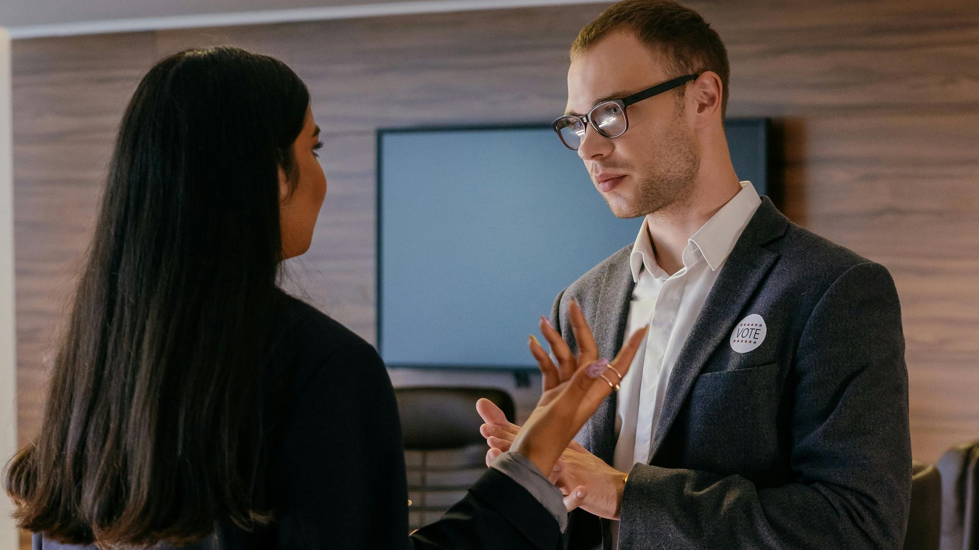 Two professionals engaged in conversation in a modern conference room setting.