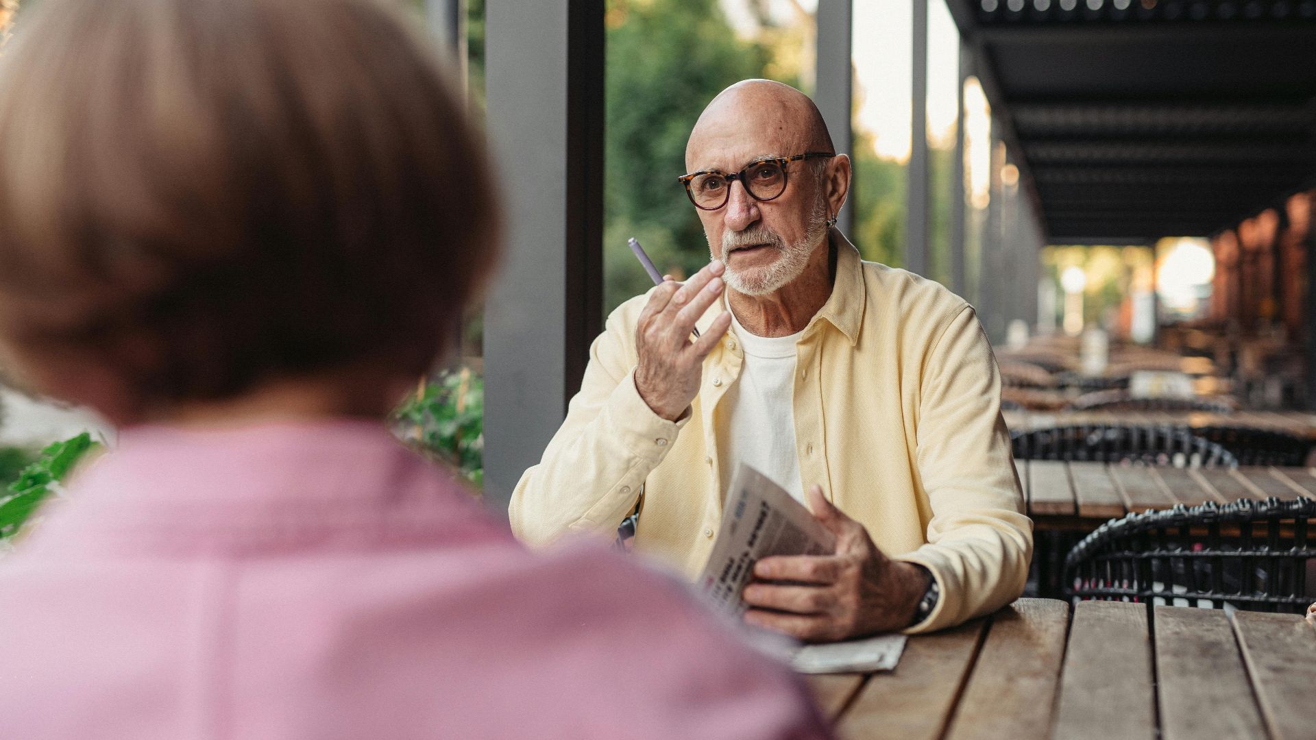 Elderly couple conversing at an outdoor cafe, enjoying a peaceful moment together.