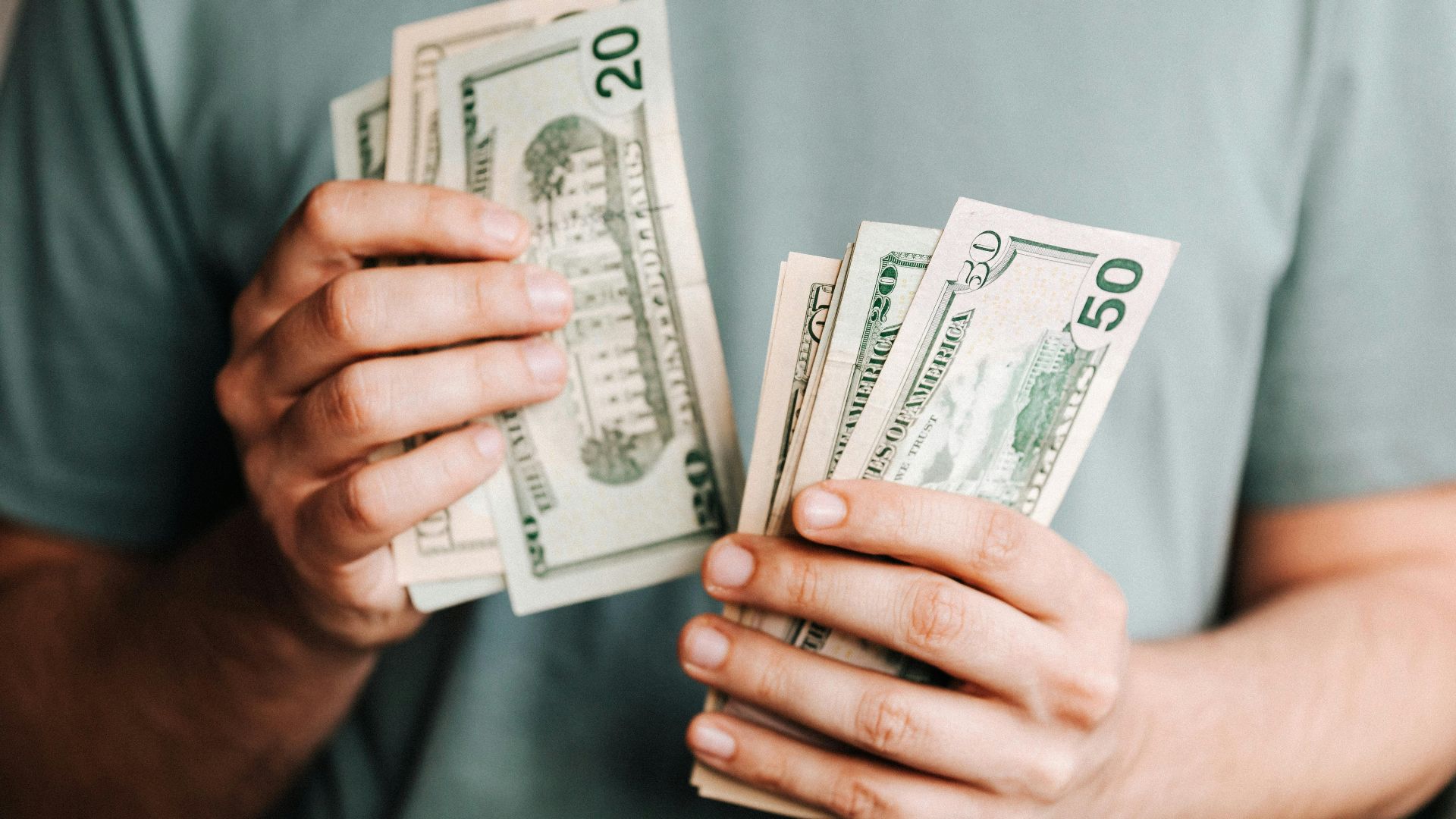 Close-up of a person counting US dollar bills indoors. Financial concept.