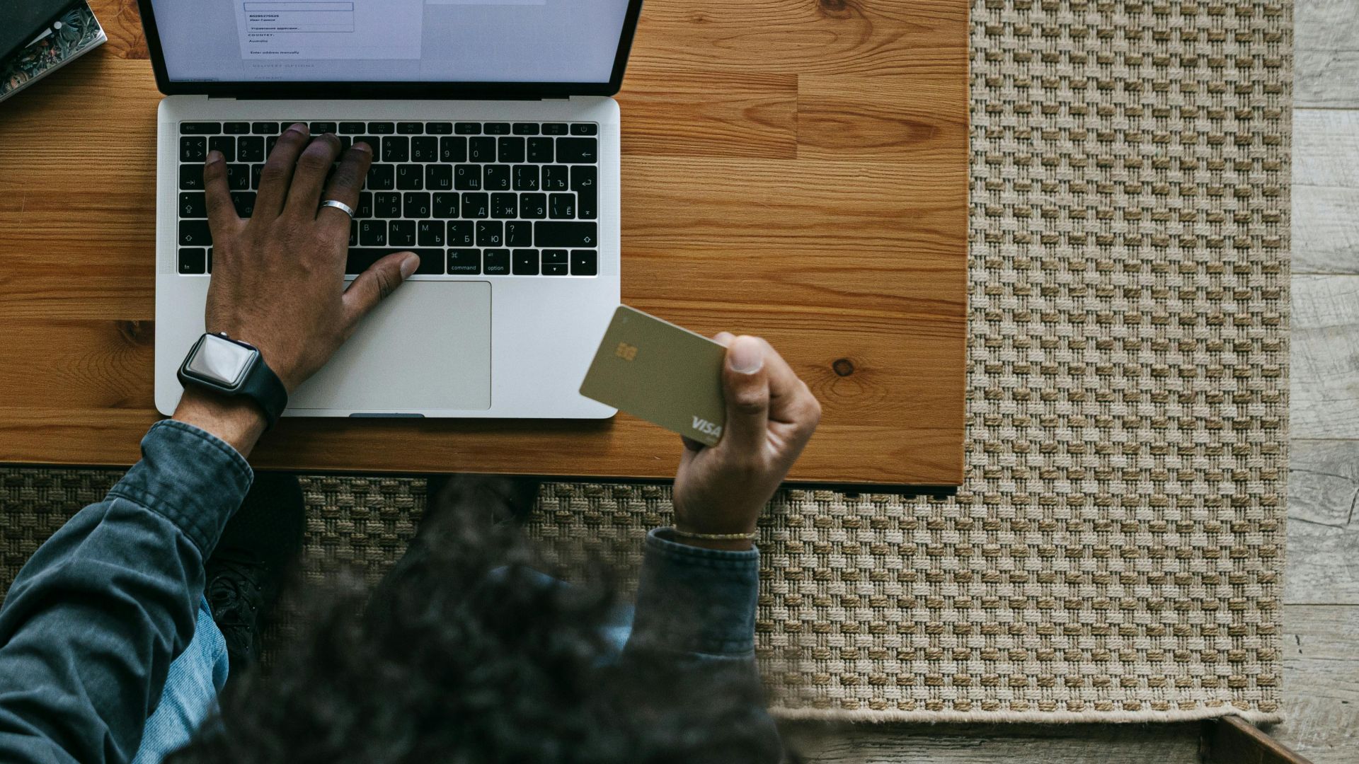 Overhead view of a person using a laptop and credit card for online shopping.