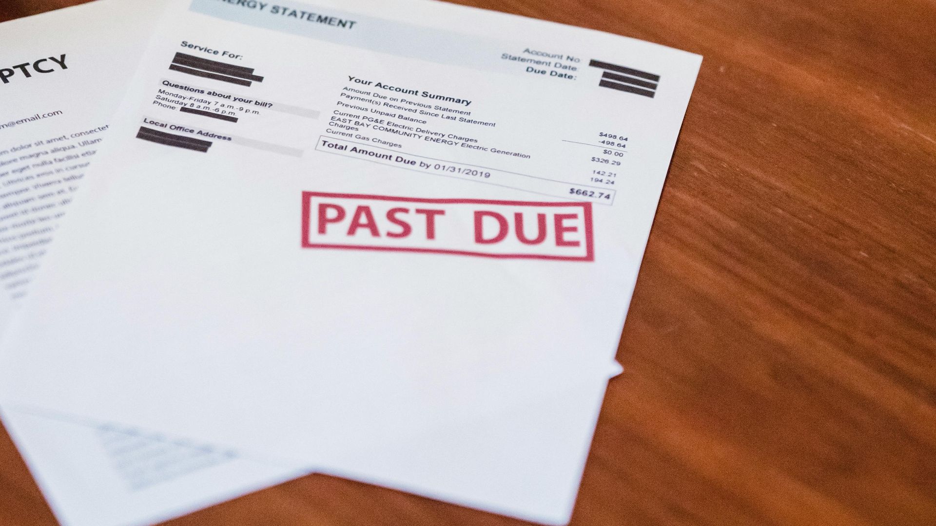Close-up of past due financial documents on a wooden table, suggesting economic hardship.