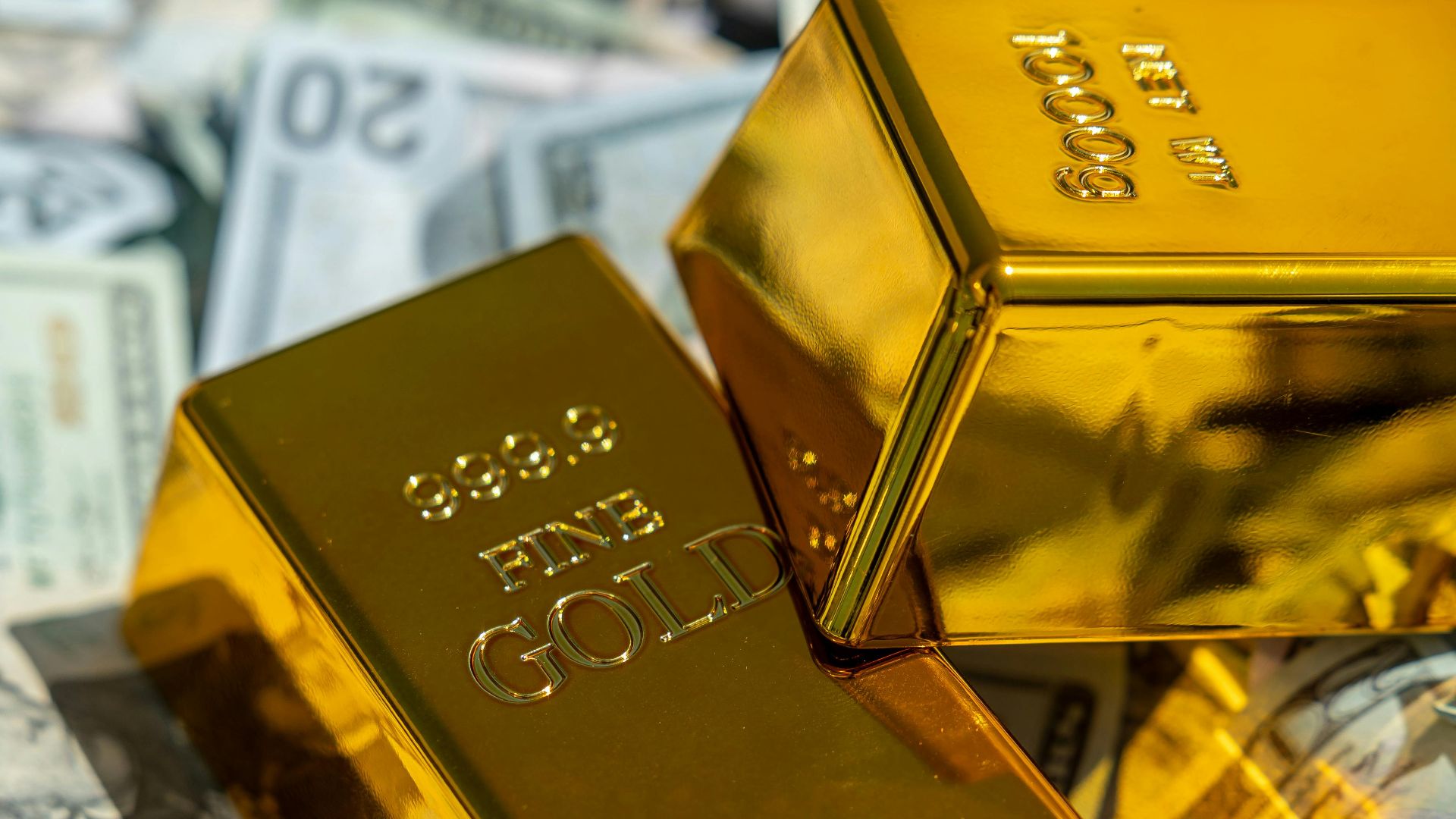 Close-up of gold bars atop US currency, symbolizing wealth and investment.