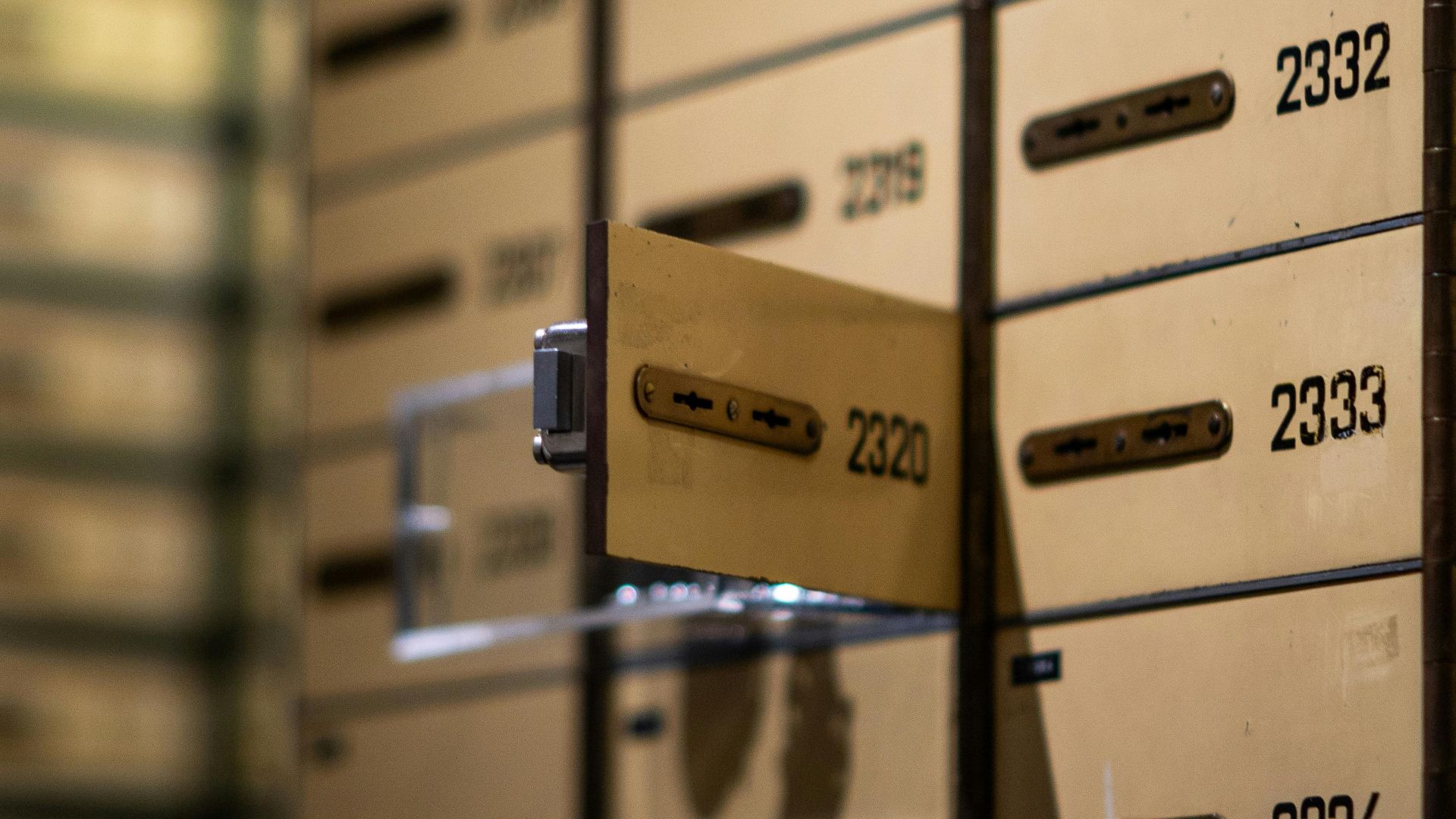 Vertical shot of metallic lockboxes with numbers in a bank vault.