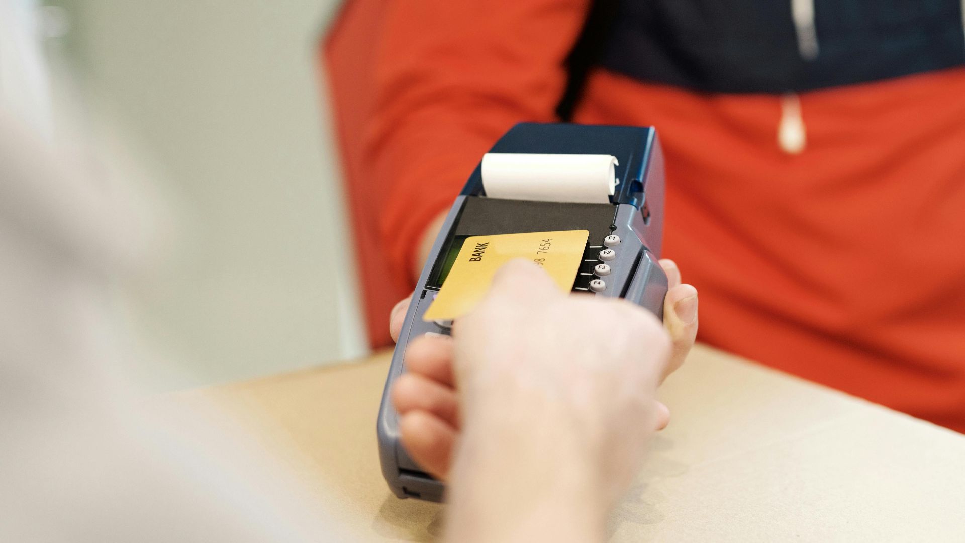 Close-up view of a contactless payment transaction using a credit card on a terminal device.