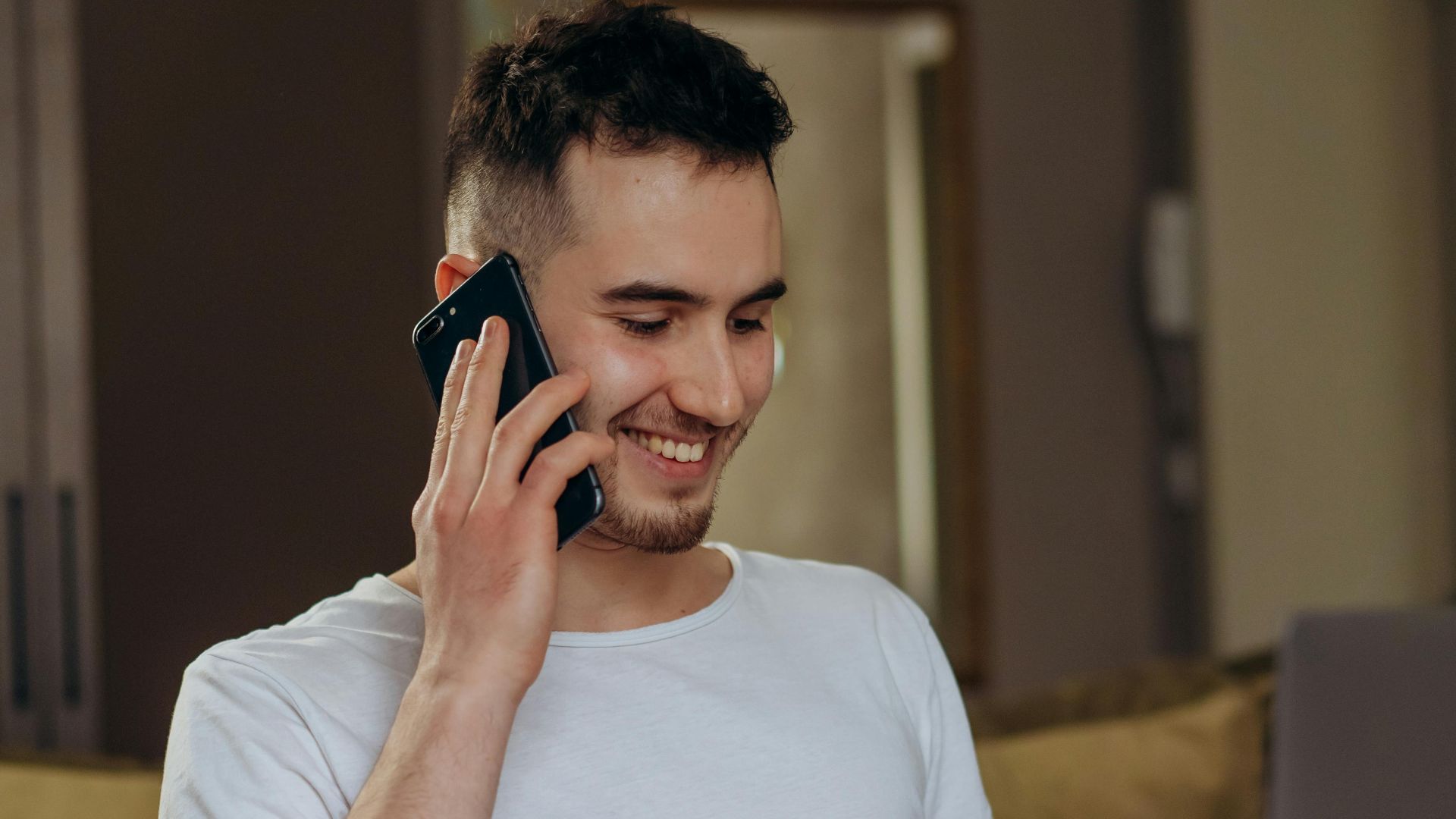 Young man multitasking with a phone and credit card while online shopping on his laptop at home.