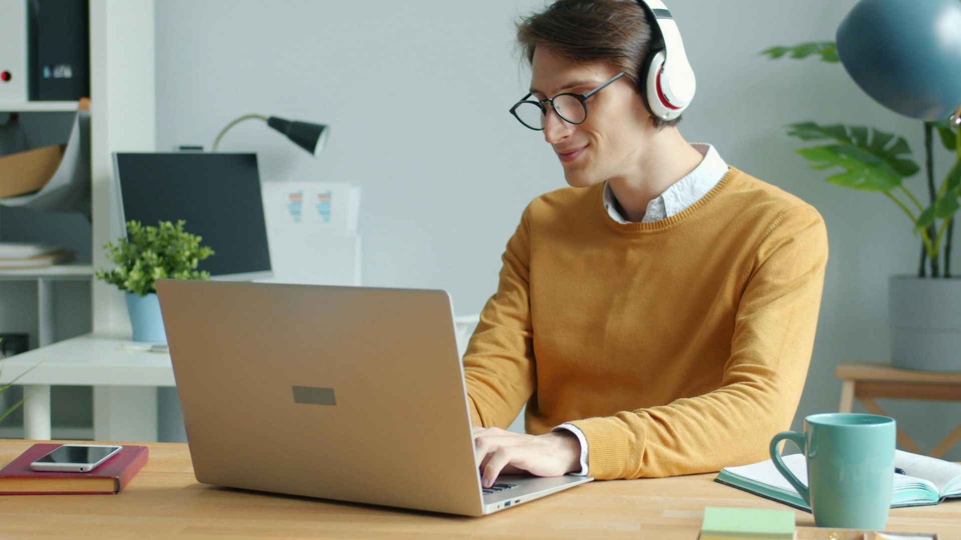 Man enjoying remote work on laptop with headphones in modern home office.