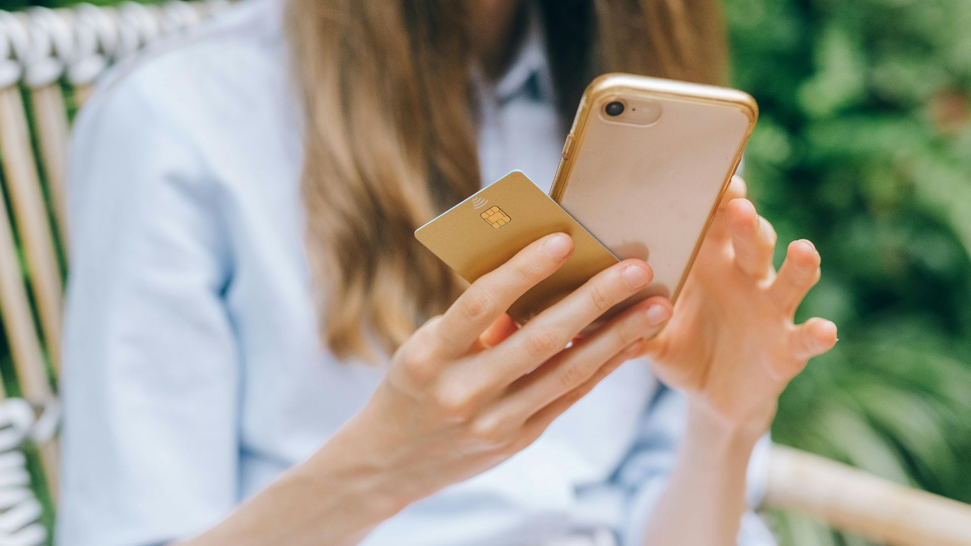 A woman making an online purchase using a smartphone and credit card outdoors.