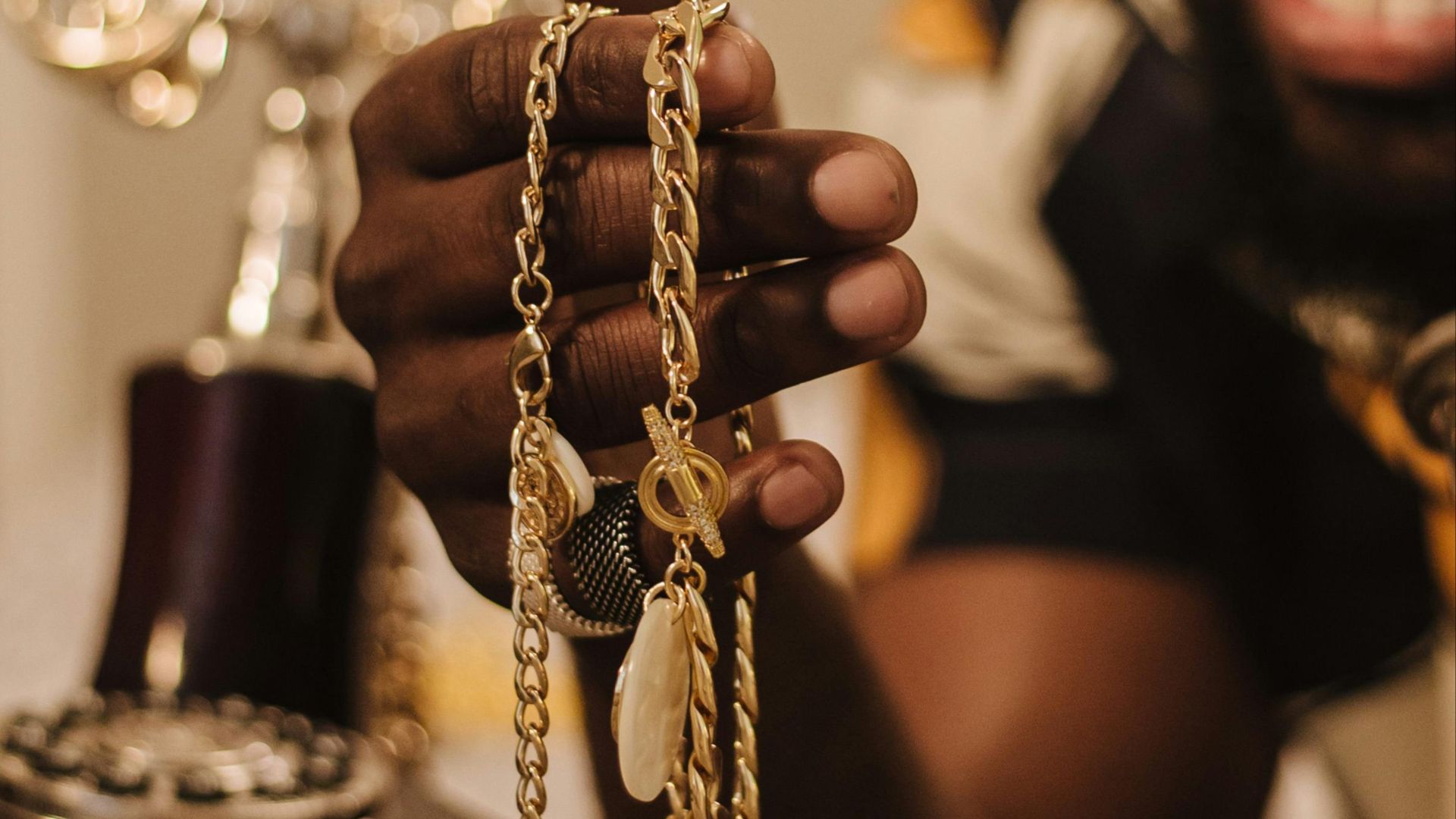 A smiling man holding intricate gold chains with a vintage phone nearby, creating a warm and luxurious ambiance.