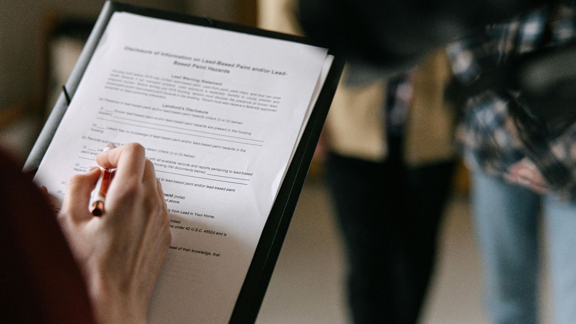 A couple examines real estate documents indoors with focus on writing and discussion.