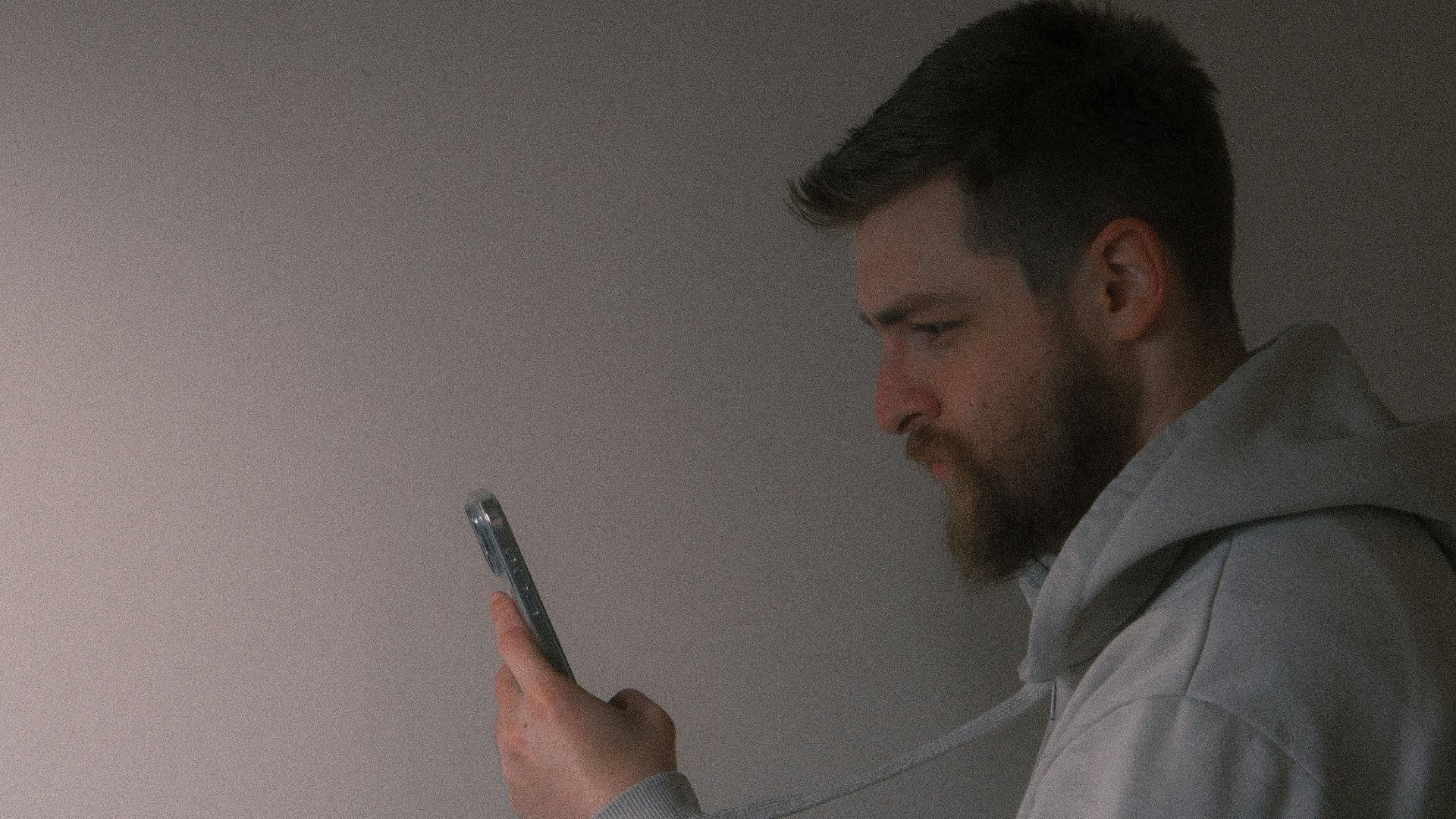 a man holding a cell phone next to a plant