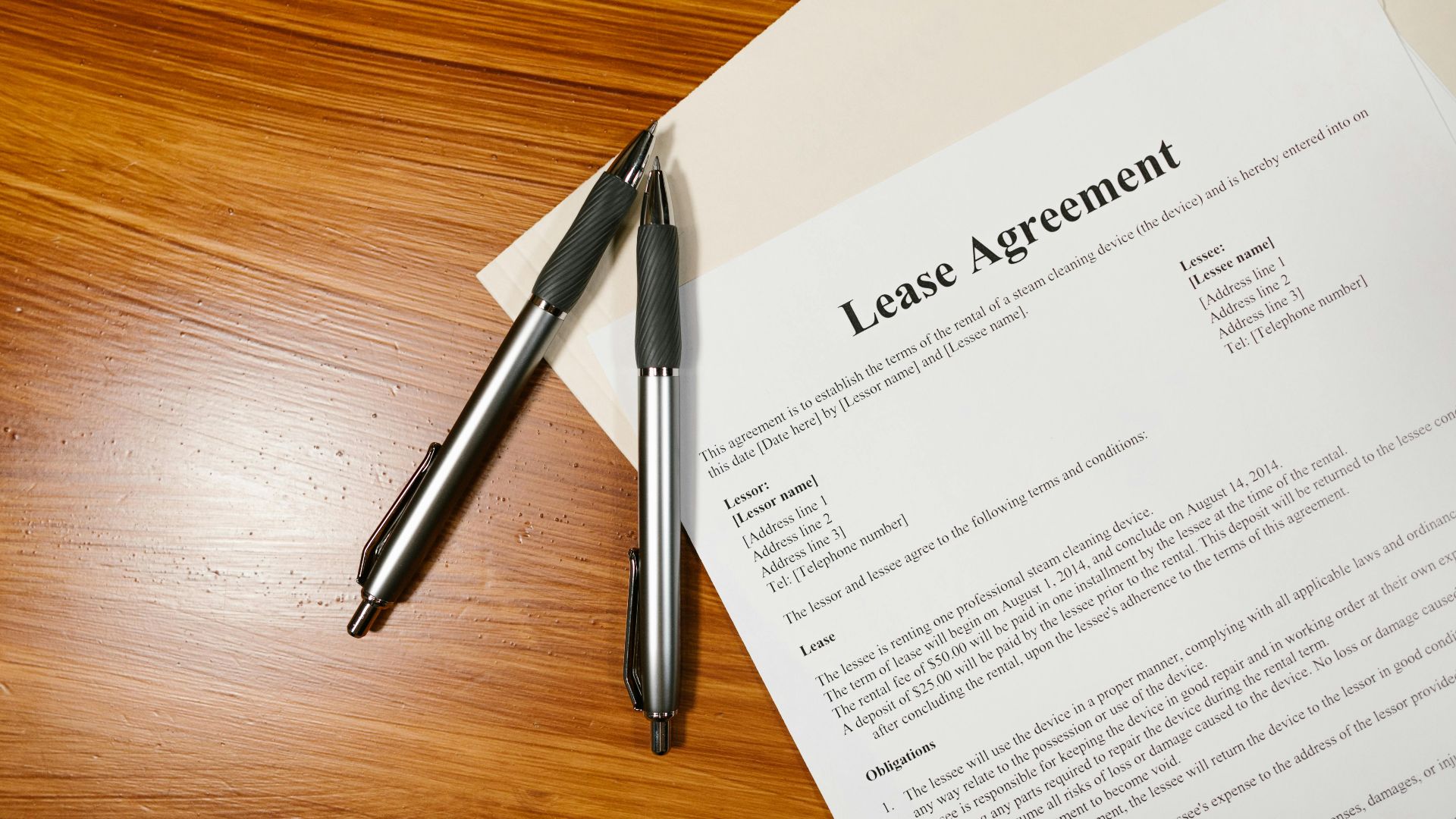 High-angle view of a lease agreement and pens on a wooden desk.