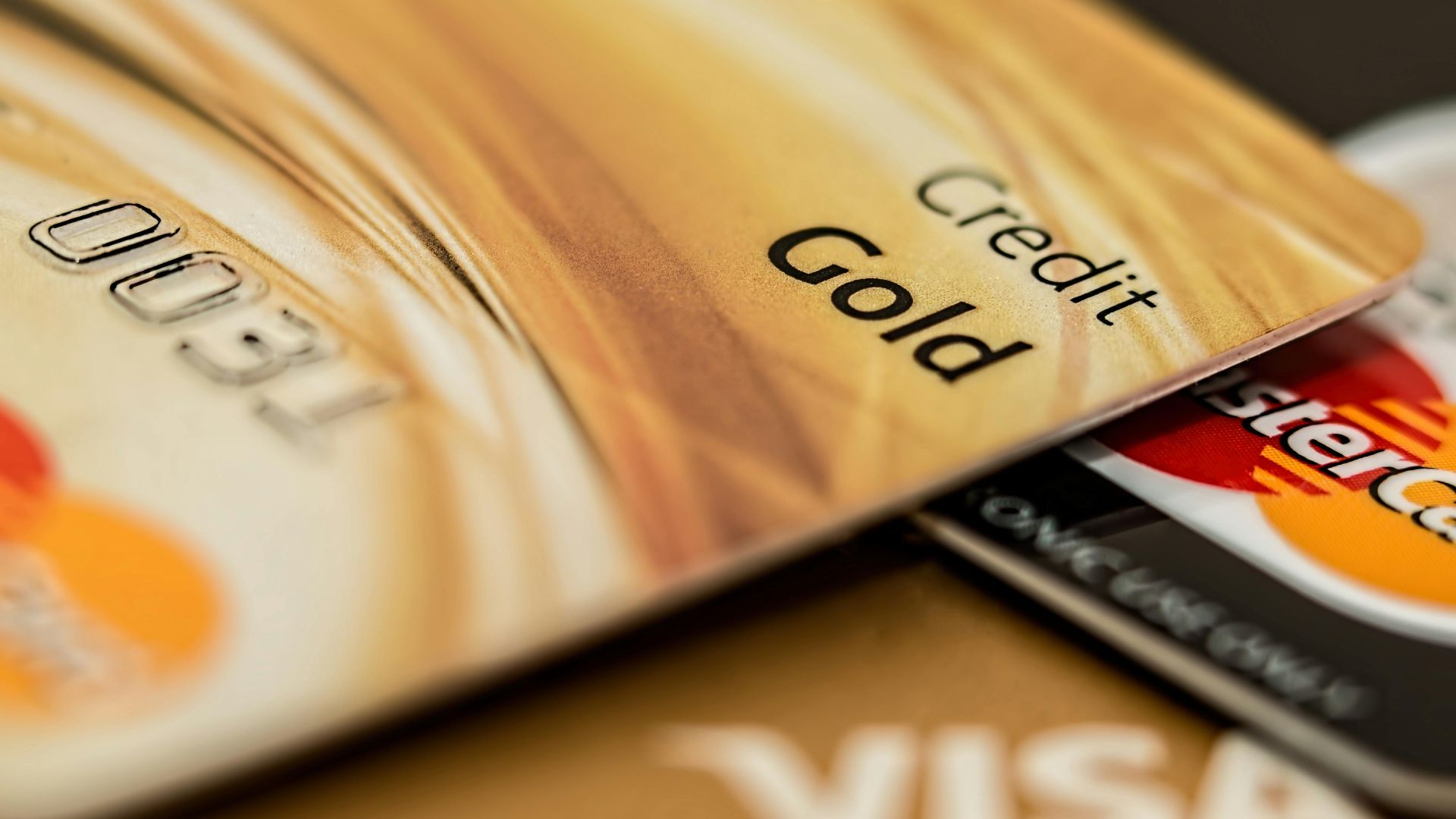 Stack of various branded credit cards focusing on gold card showing finance and cashless concept.