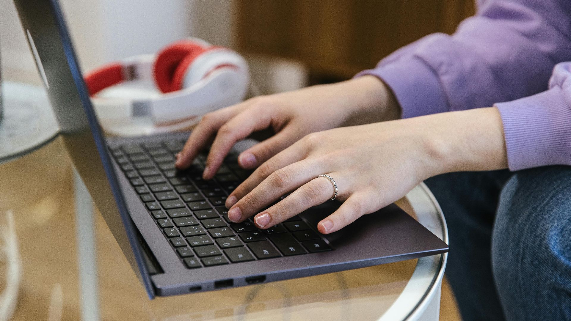 Close-up view of hands typing on a laptop indoors, showcasing technology and productivity.