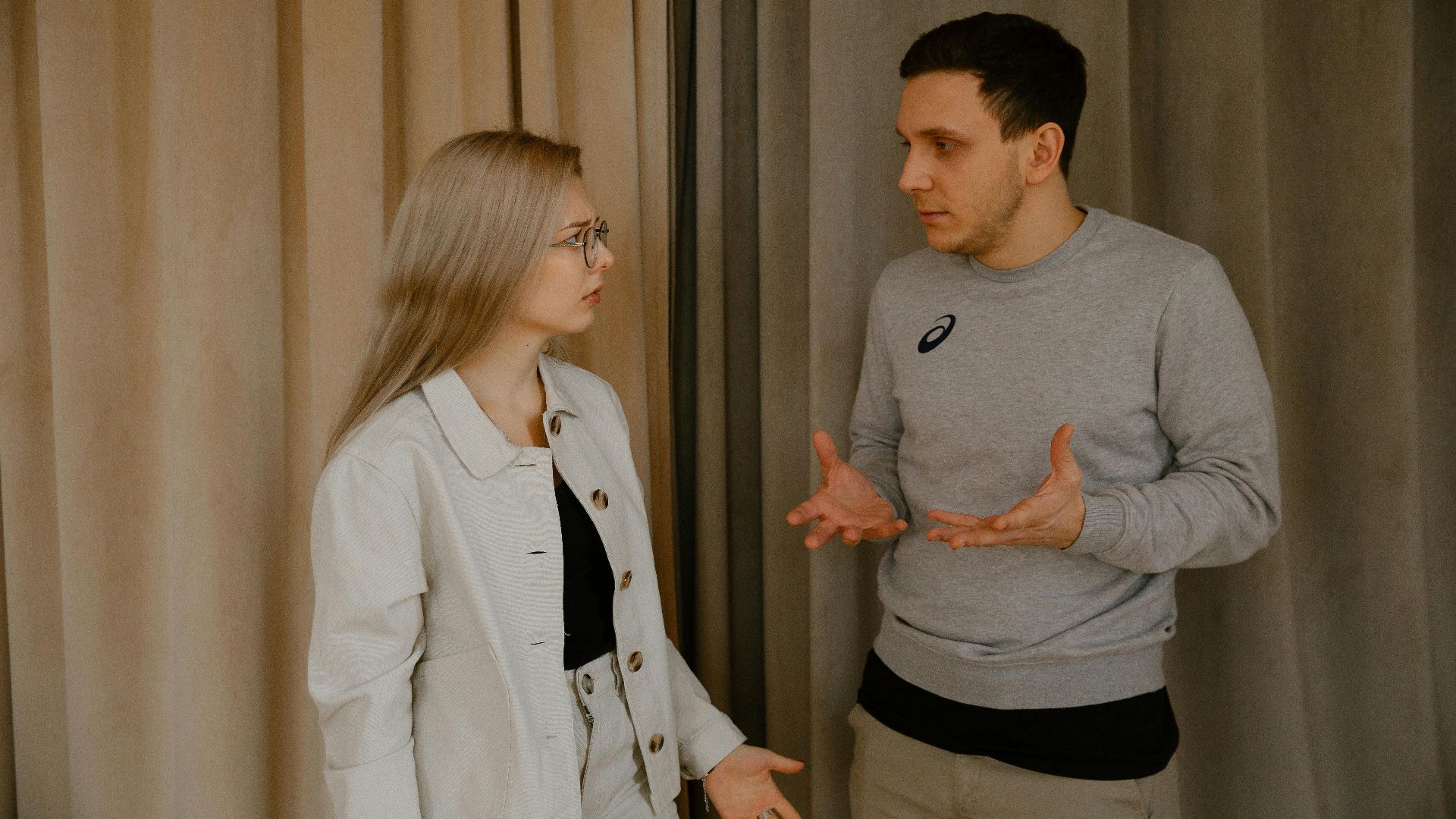 A young couple passionately discussing indoors, capturing intense emotions and gestures.