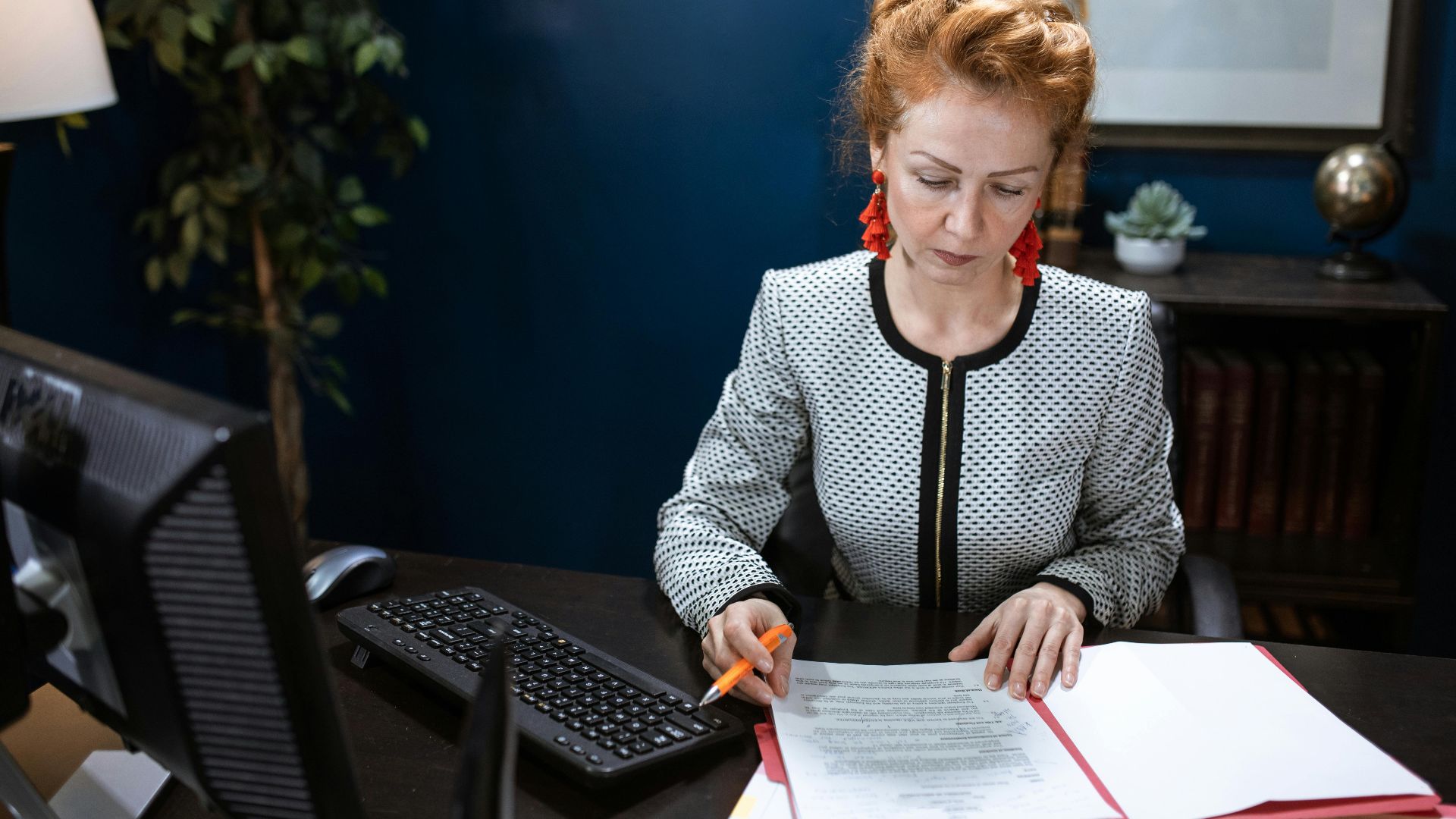 A focused woman working on paperwork in a modern office environment.