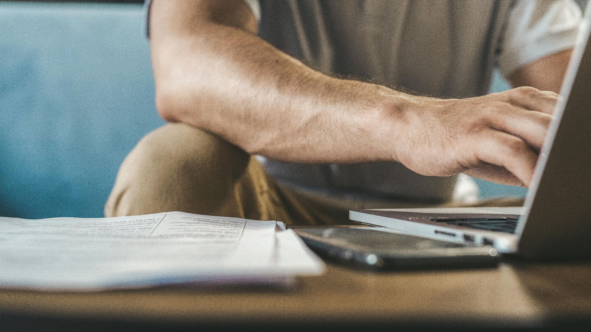 A man typing on a laptop at home, using wireless technology.