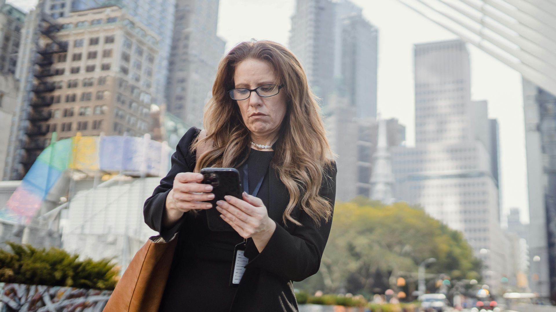 Businesswoman on phone in city street against modern skyscrapers.
