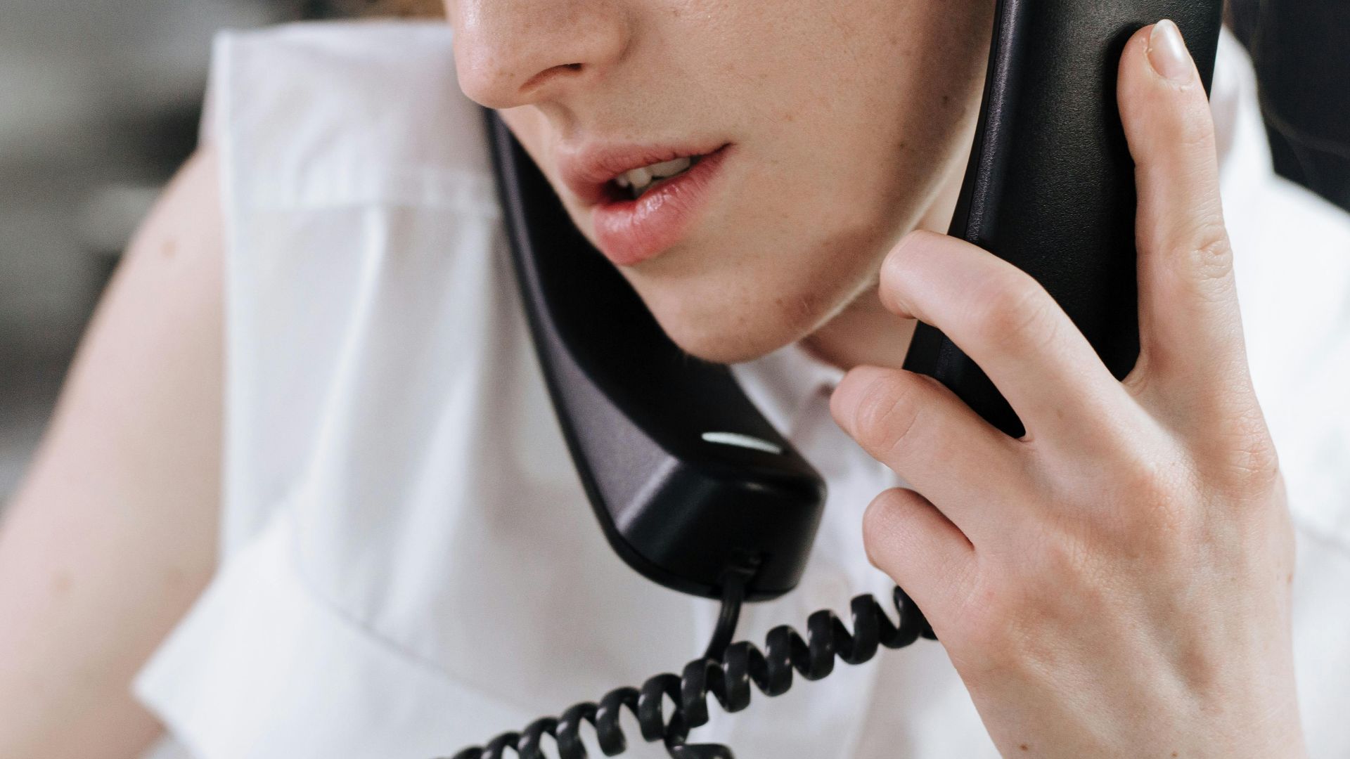 Close-up of a woman talking on a phone in an office setting.