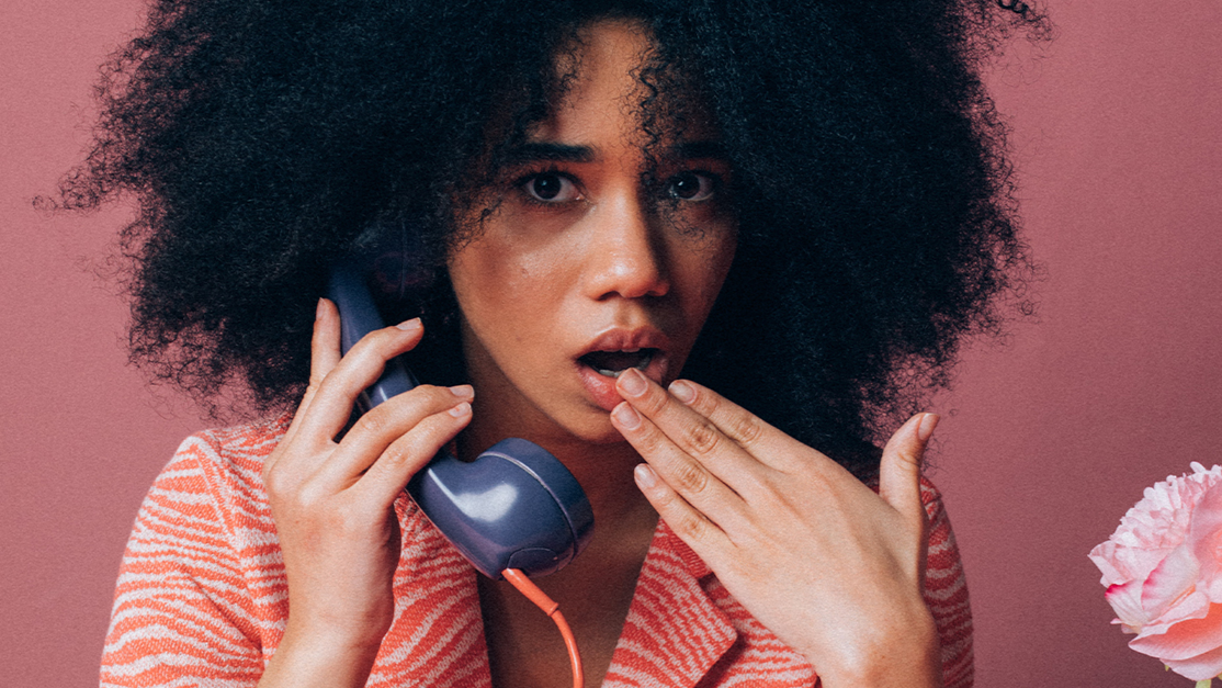 Woman Looking Surprised while Using an Old Telephone