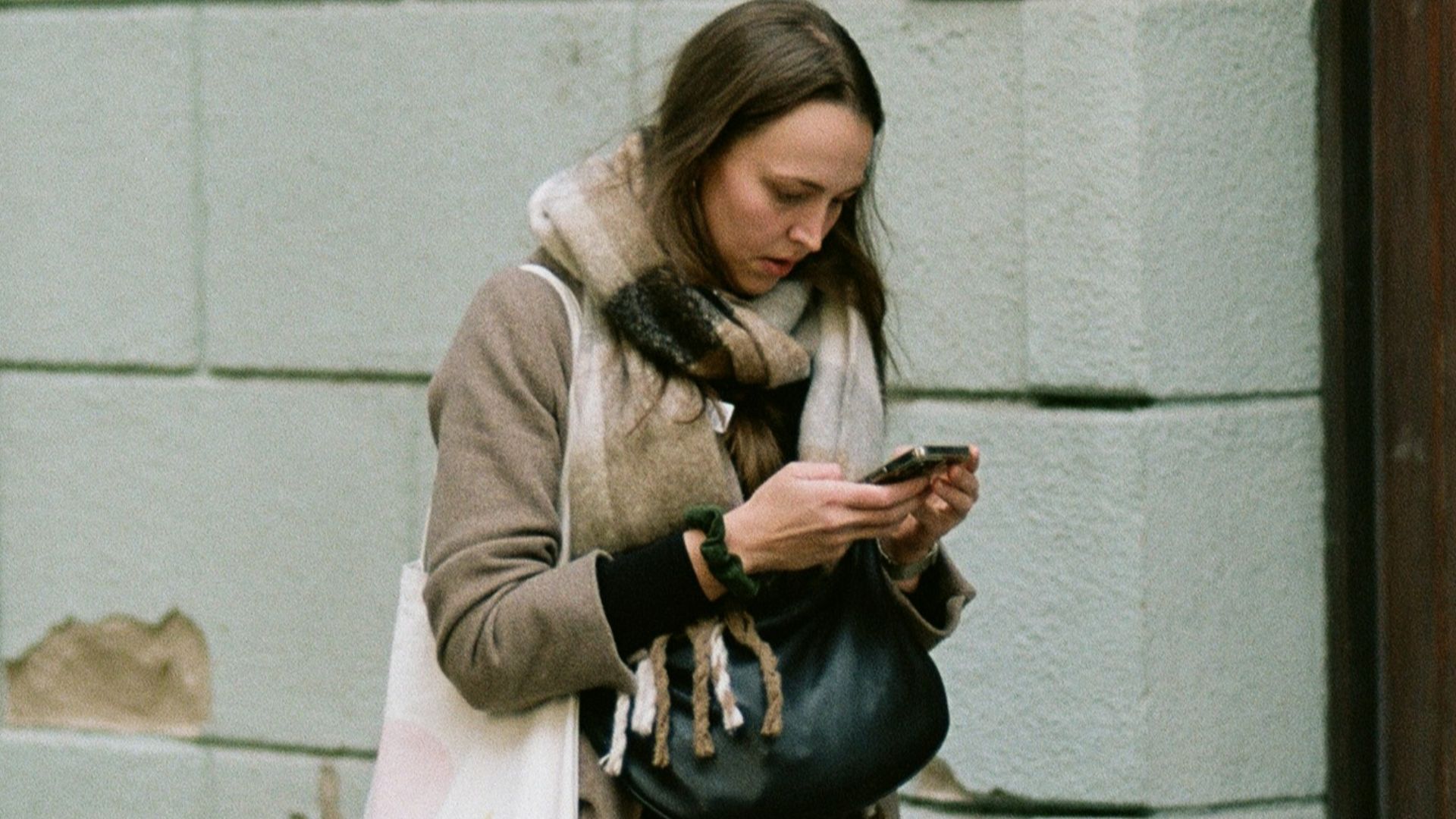A woman standing on a sidewalk looking at her cell phone