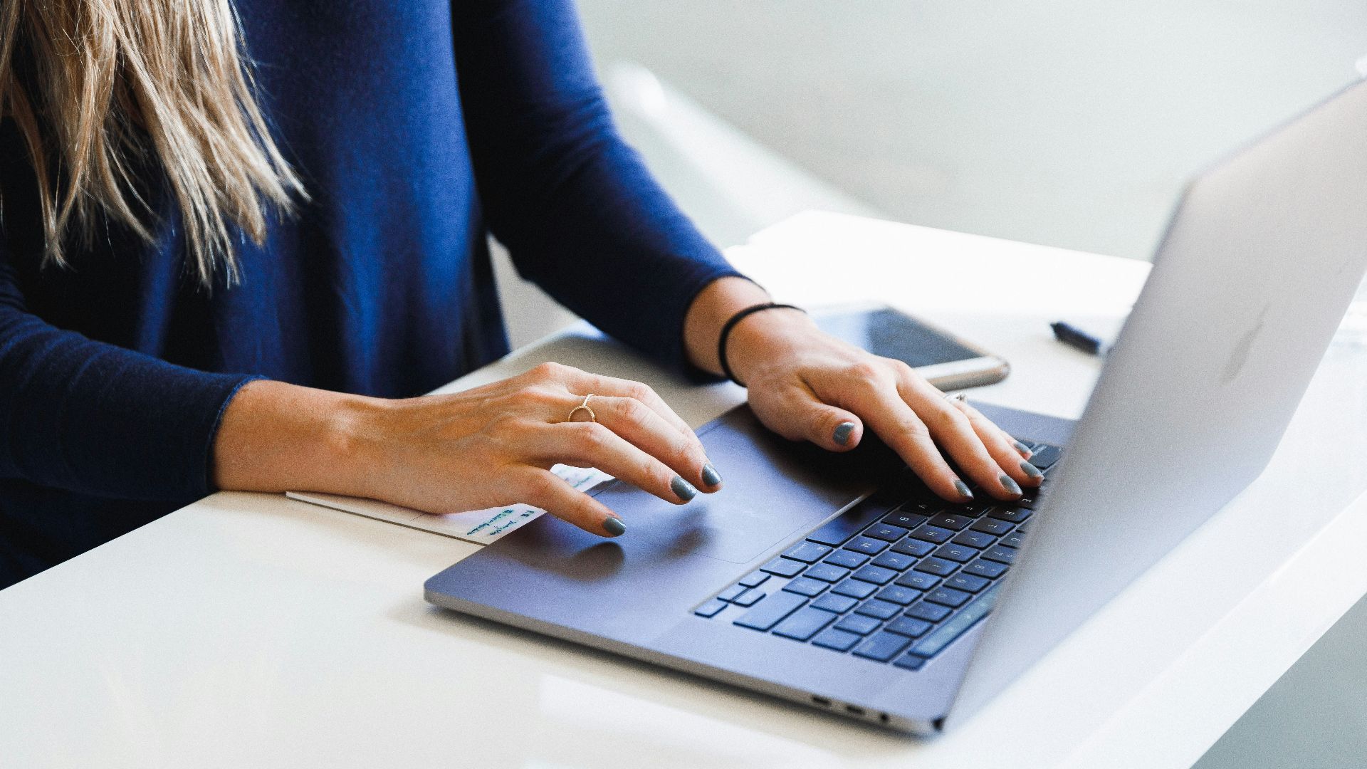 woman in blue long sleeve shirt using macbook pro