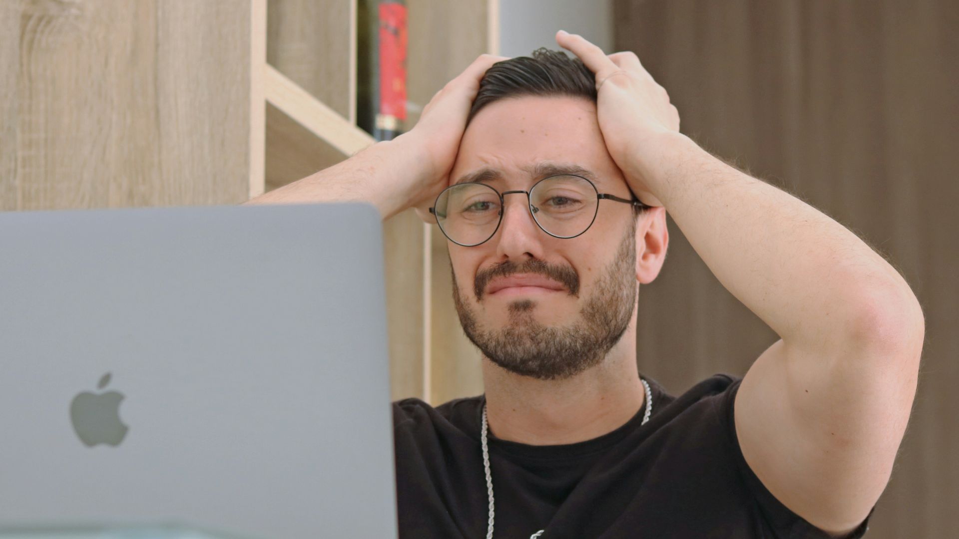 a man with glasses is looking at a laptop