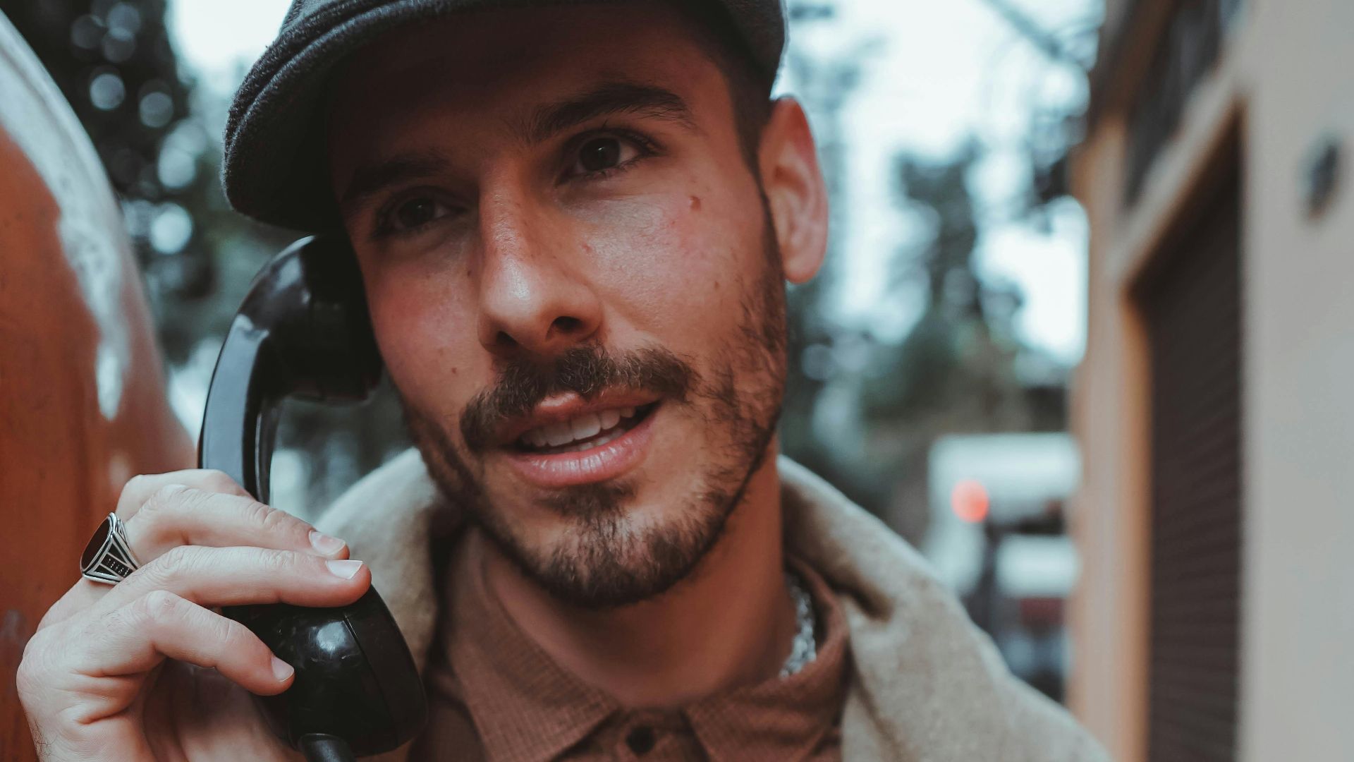 Casual man with beard using a public telephone outdoors in São Paulo, Brazil.