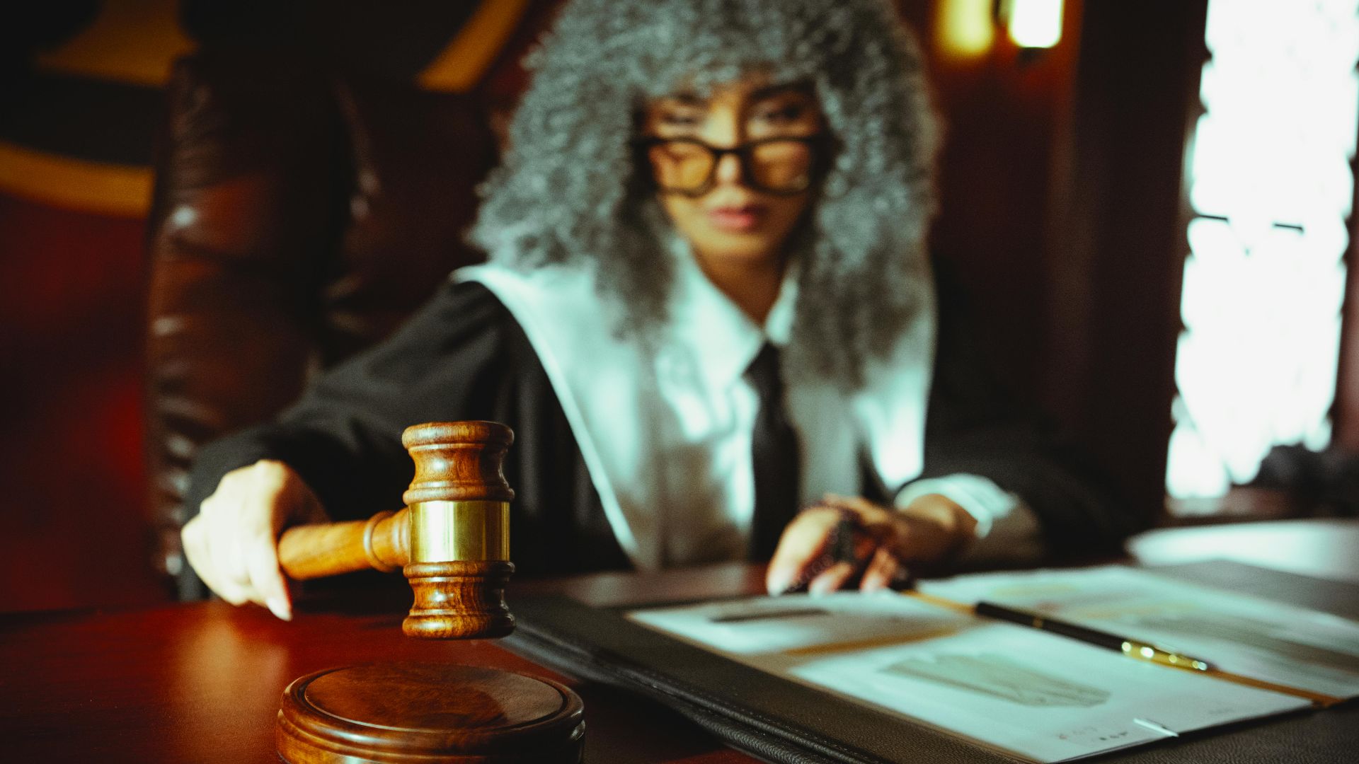 A judge in a courtroom holding a gavel, focused on legal documents.