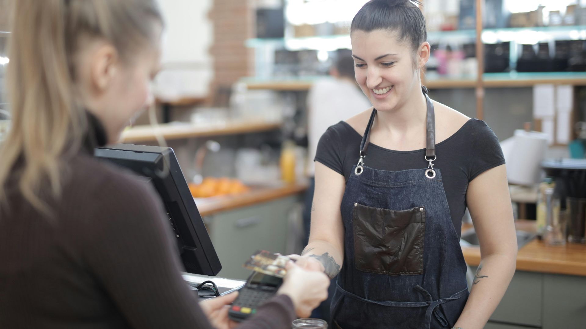 Smiling cashier helping customer with payment at store counter.