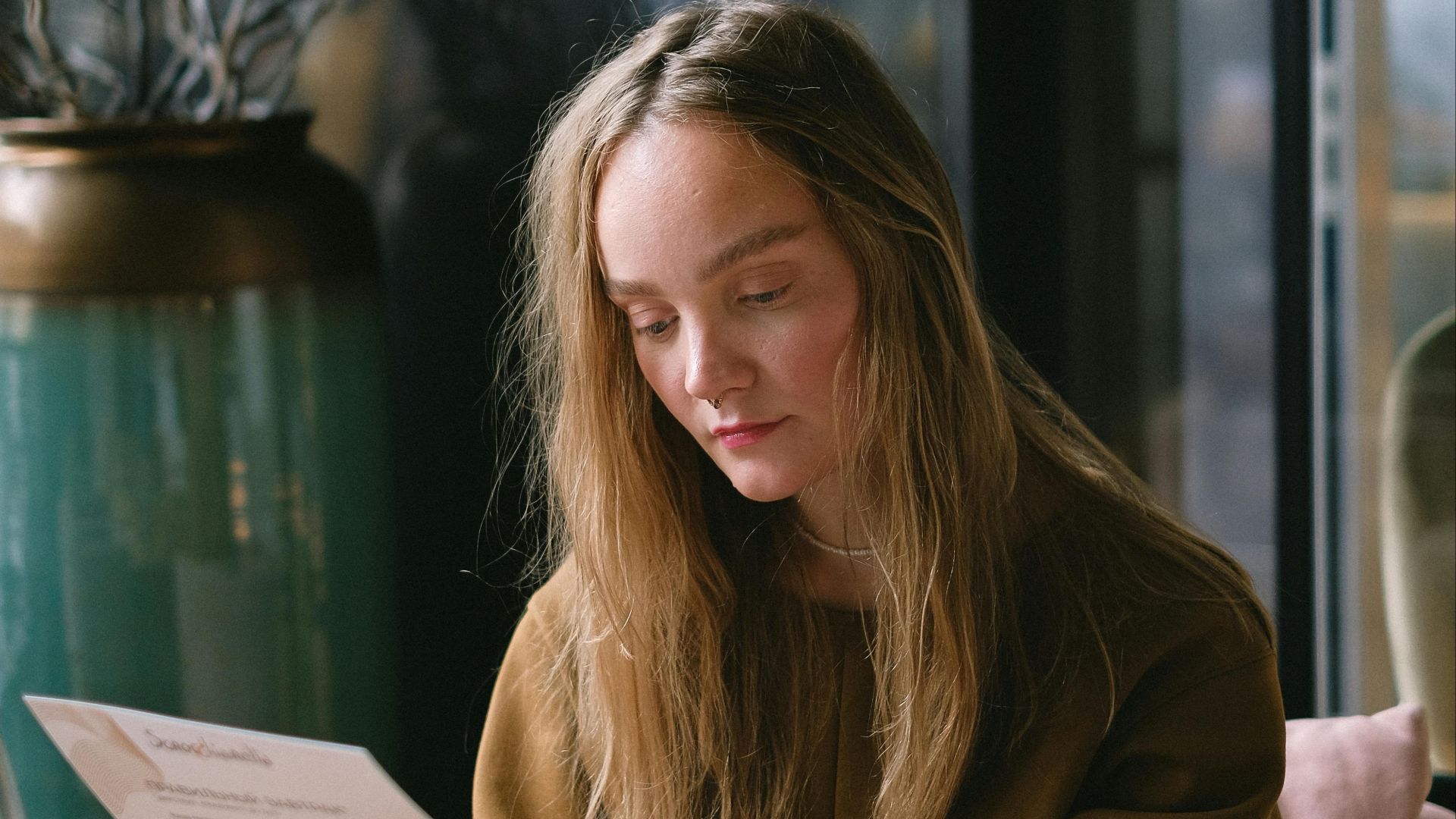 Young woman reading a menu in a warm, inviting restaurant interior.