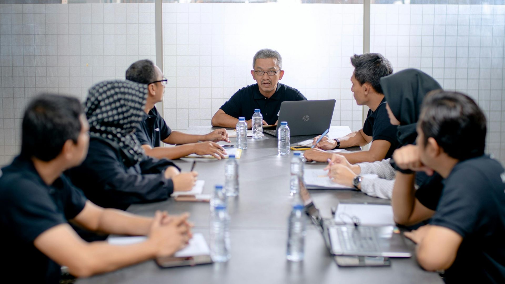 Professional team meeting around a conference table in an office setting.