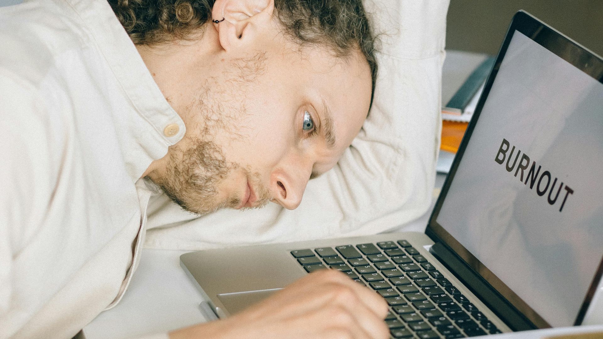 Exhausted employee with head on desk, facing workplace burnout stress.