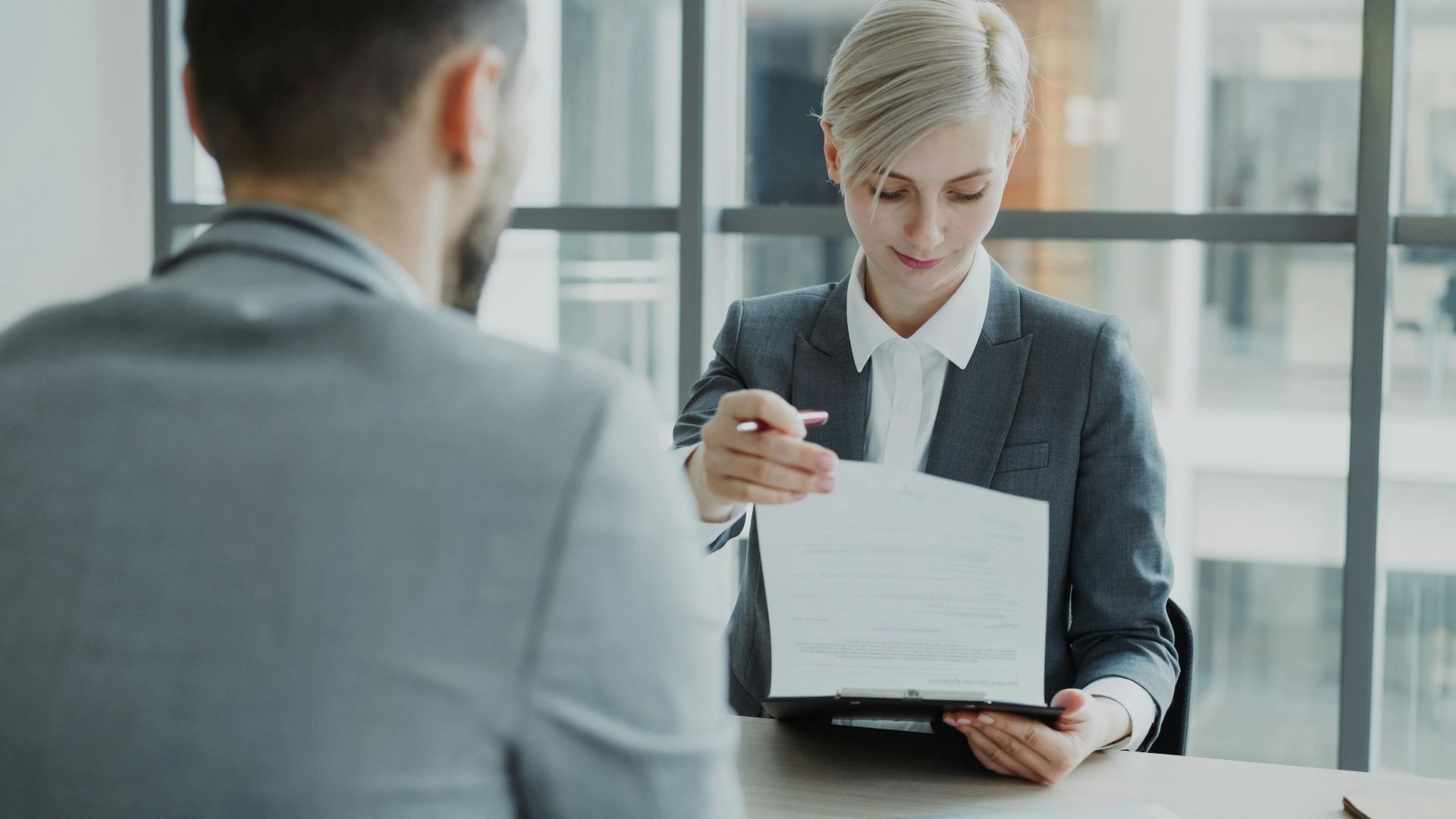 Business professionals reviewing a contract in a modern office setting.