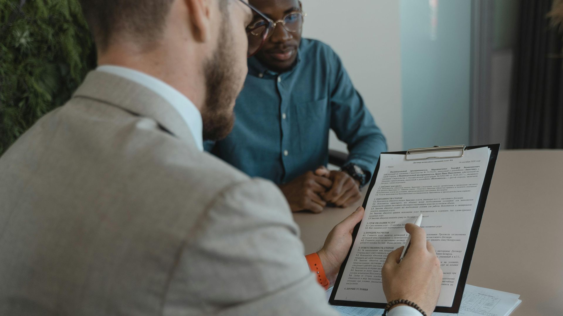 A recruiter reviews a candidate's documents during a job interview in a modern office setting.