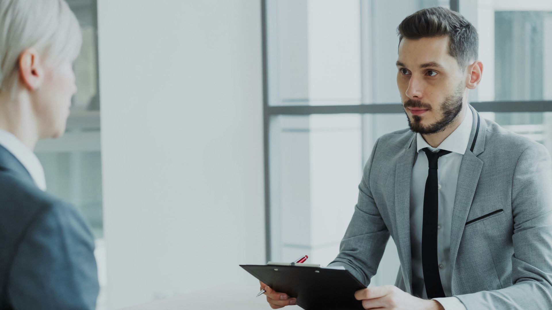 Two people in a business meeting with a clipboard.