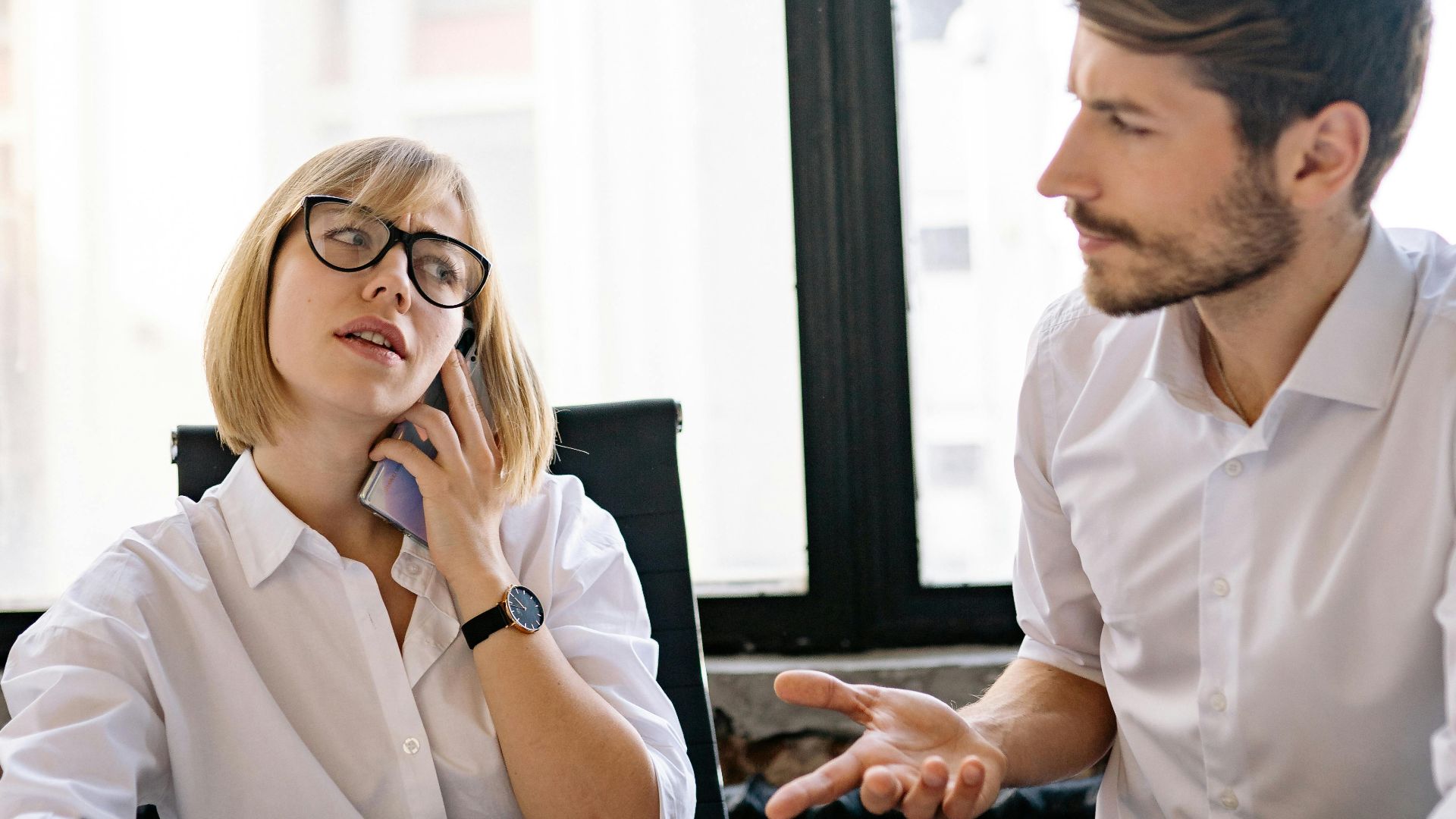 A businessman and businesswoman engage in a meeting in a modern office setting, emphasizing teamwork and communication.