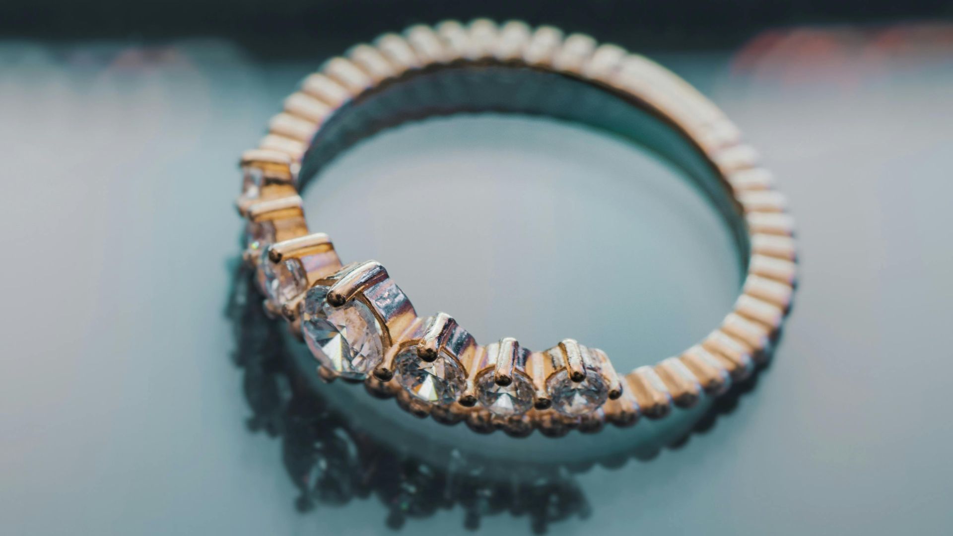 Close-up of a gold ring with diamonds on a reflective surface, showcasing elegance and luxury.
