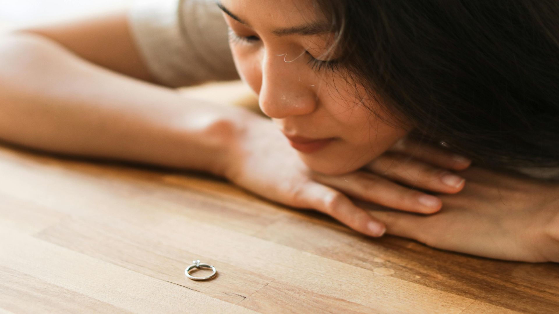 Woman gazing at a wedding ring, contemplating relationship decisions.