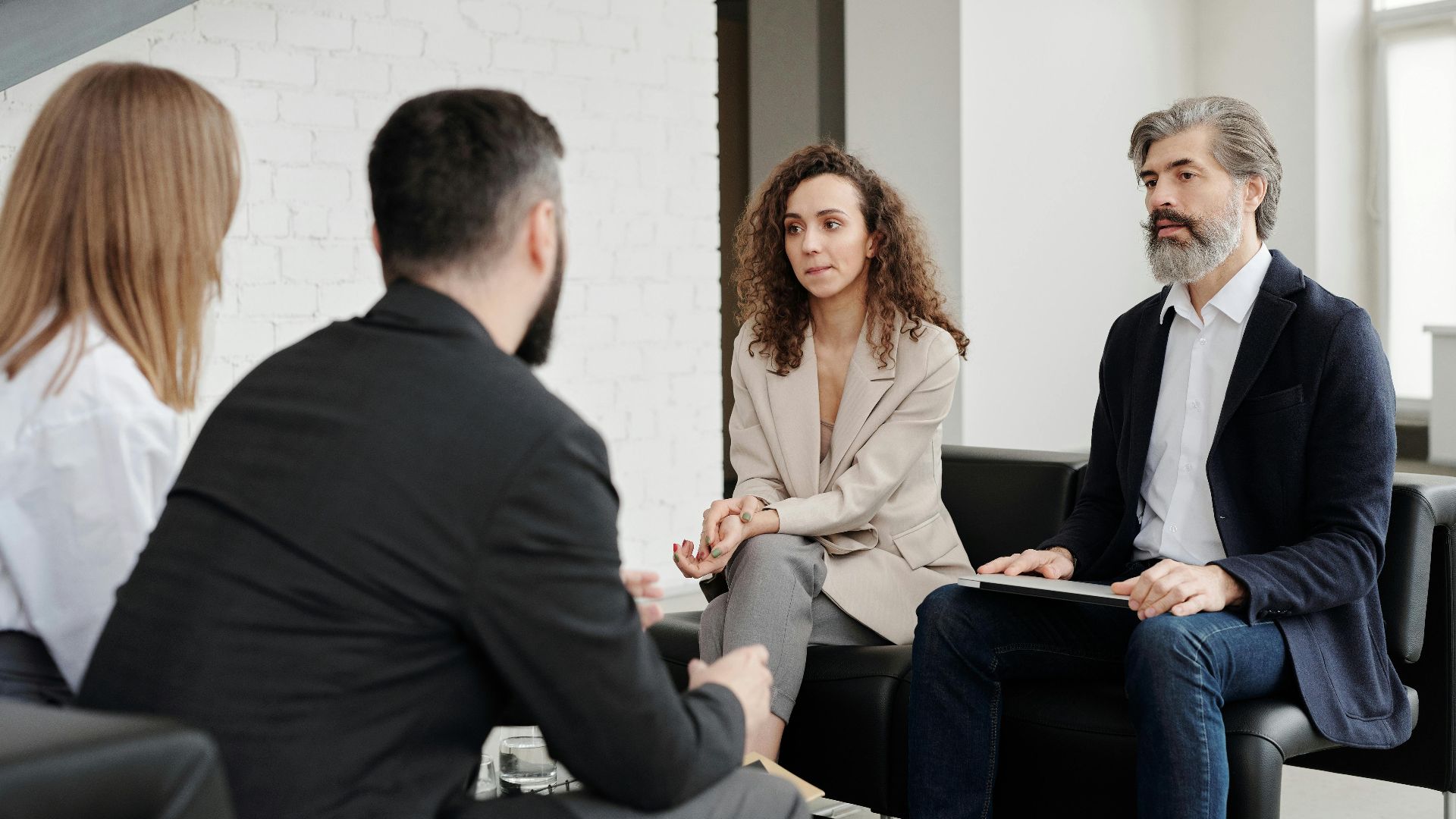 Four professionals engaged in a serious business discussion indoors.