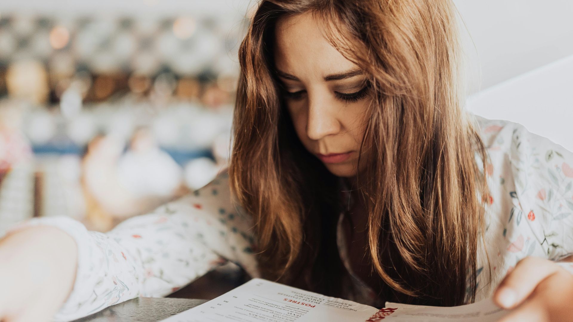 Young woman intensely focused on reading a menu inside a café, creating an introspective and cozy atmosphere.