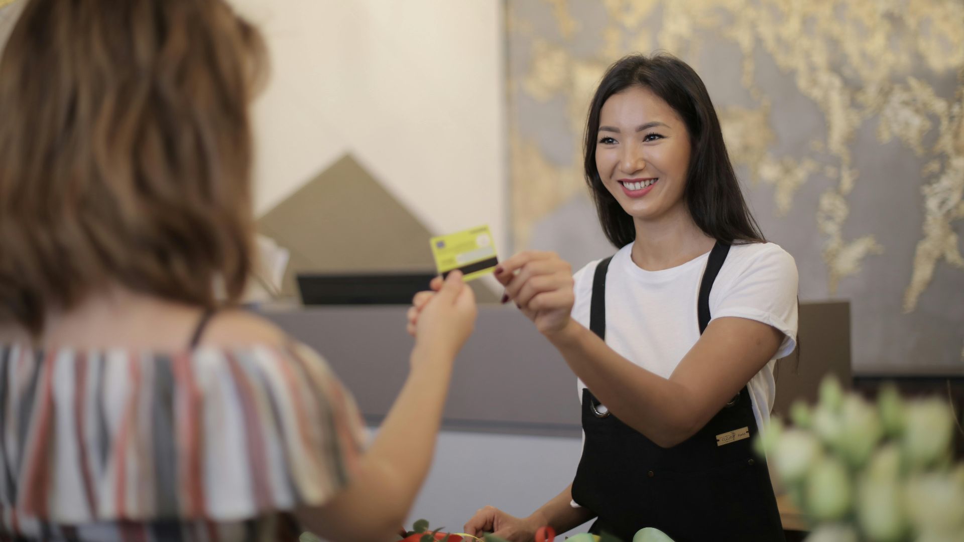 Florist smiling while accepting payment in a flower shop.