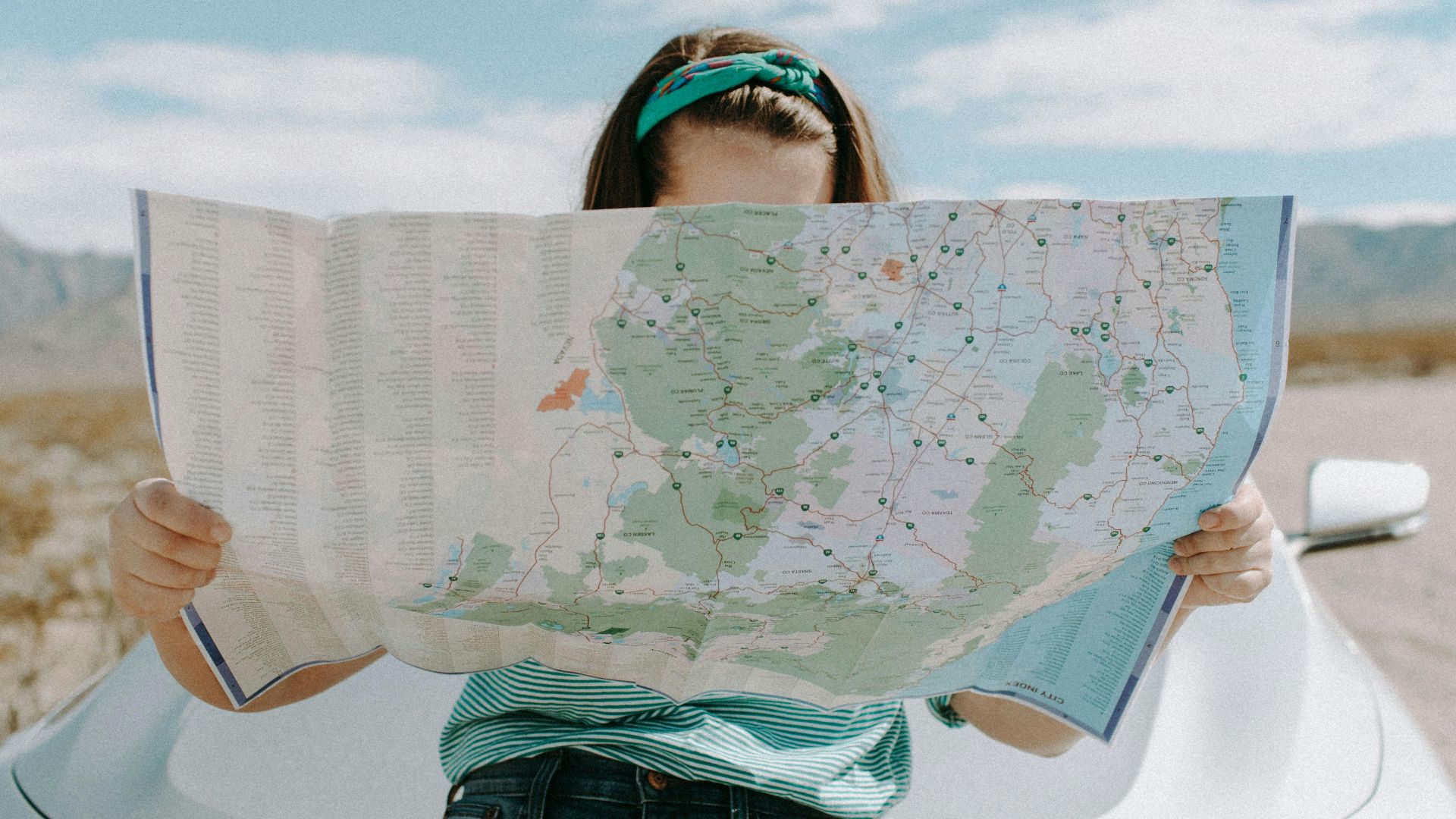 A woman holds a map while traveling through the scenic desert of California, USA.