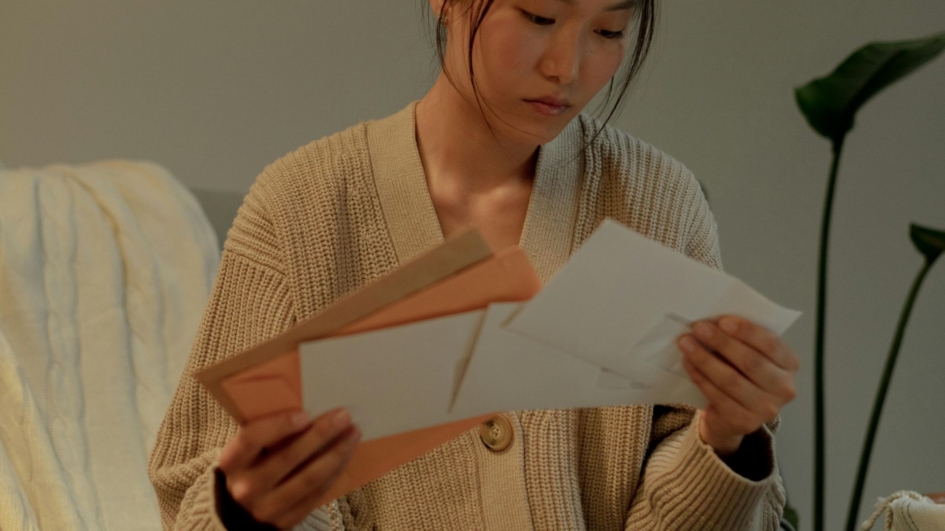 A woman seated in an armchair reads letters with focus, creating a warm, introspective mood.
